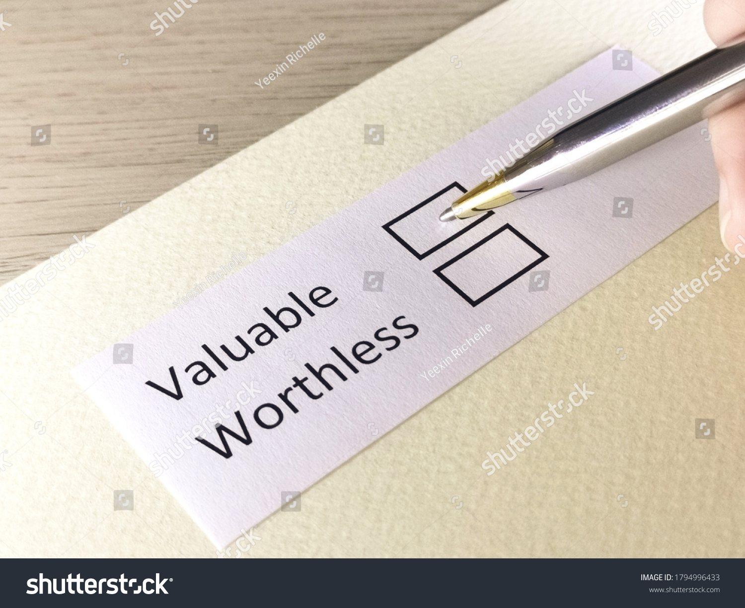 One person is answering question on a piece of paper. The person is thinking to choose valuable or worthless. #1794996433