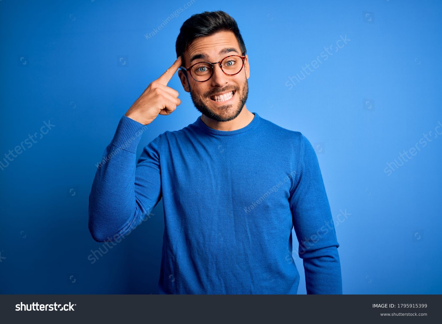 Young handsome man with beard wearing casual sweater and glasses over blue background Smiling pointing to head with one finger, great idea or thought, good memory #1795915399