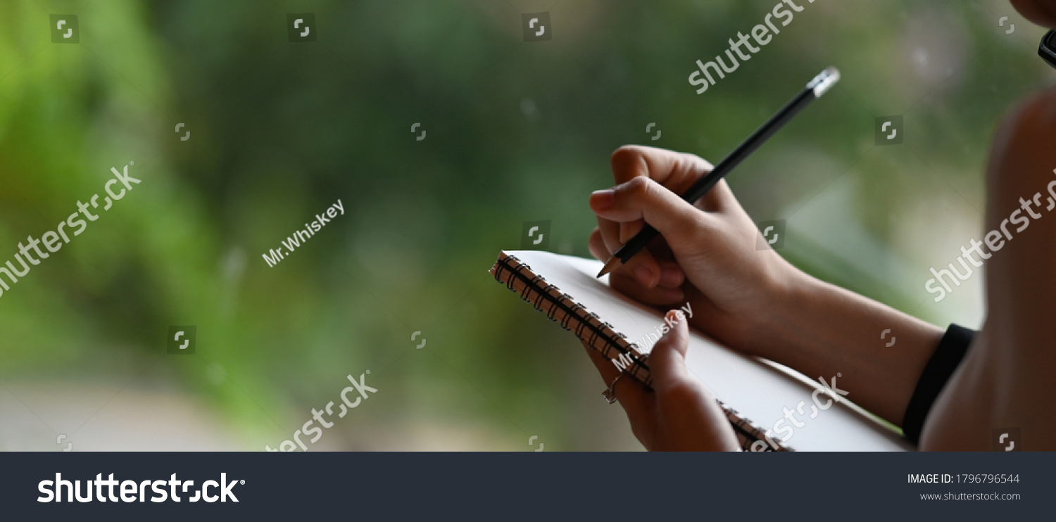 Cropped image of a businesswoman's hand is taking notes while standing over the office glass wall. #1796796544