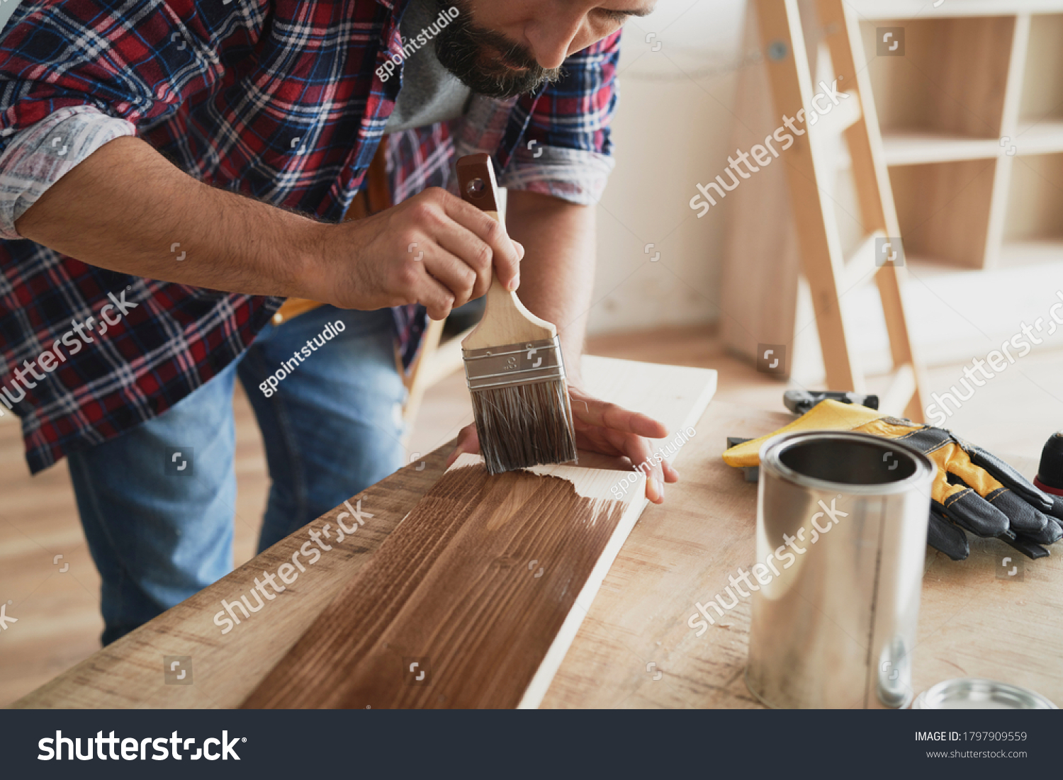 Man painting a raw board with a protective preparation                                #1797909559