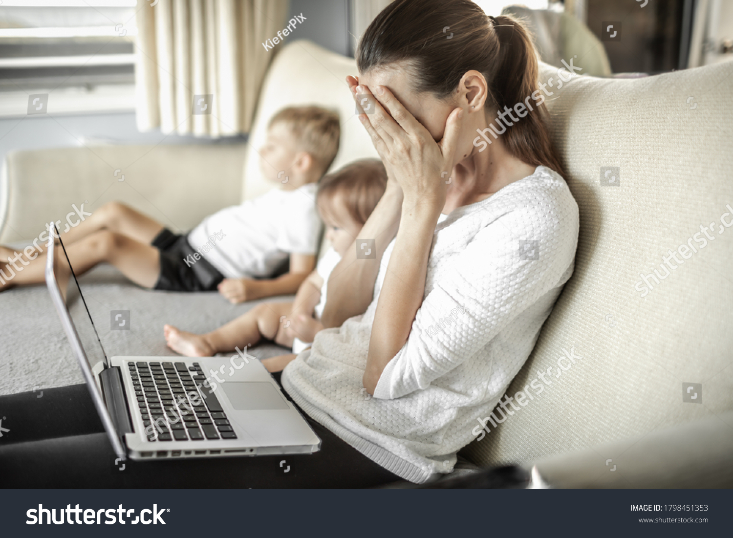 Stressed frustrated mother at home with children working on computer.  #1798451353
