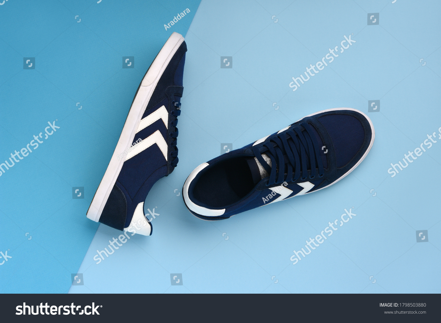 A pair of navy blue sneakers lying on a dark and light blue background. Minimal photo #1798503880