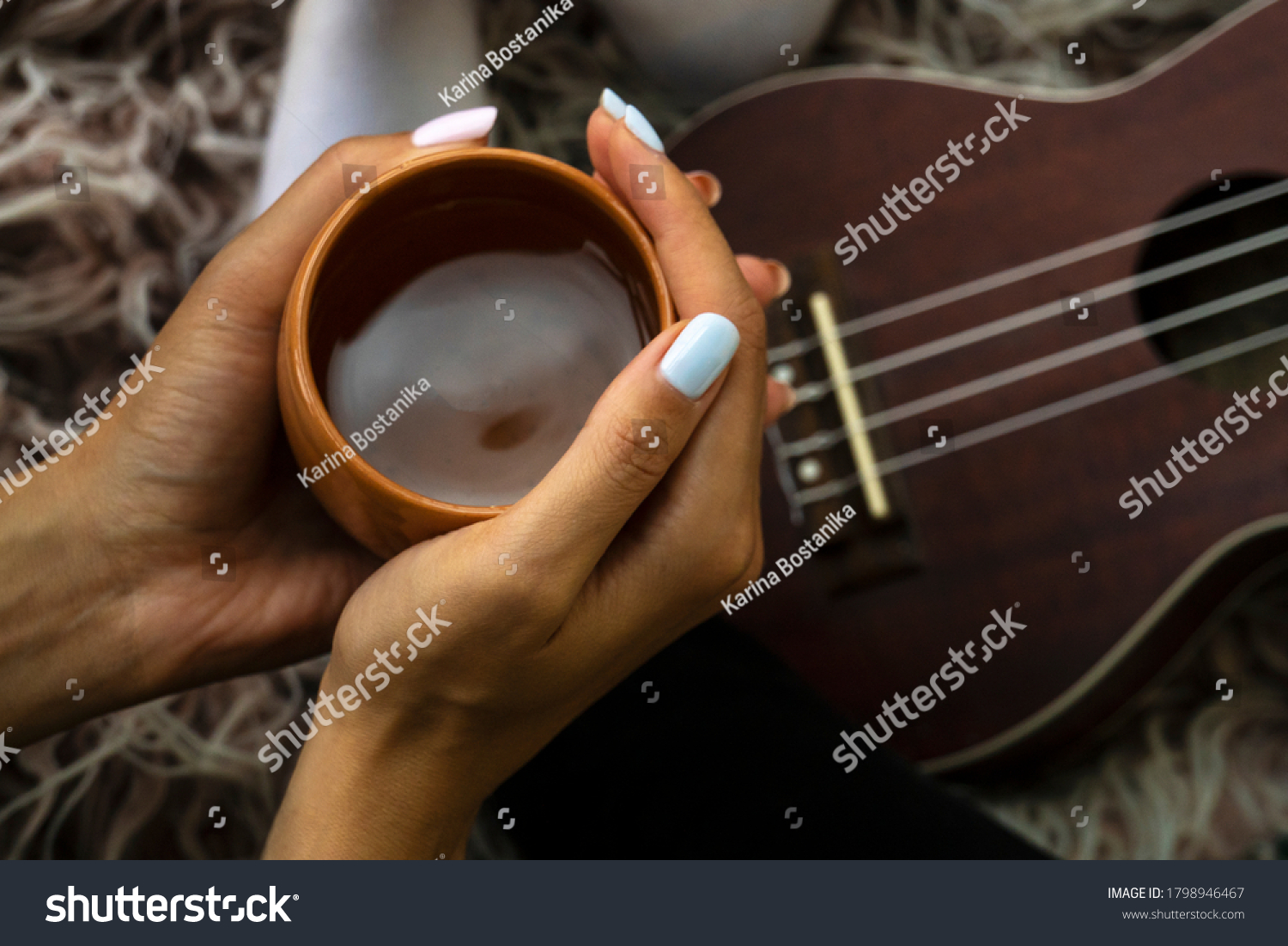 Cozy photo of woman's hands holding cup of tea with ukulele on backdrop. Fall or winter time concept. Wellbeing and simple pleasures concept #1798946467