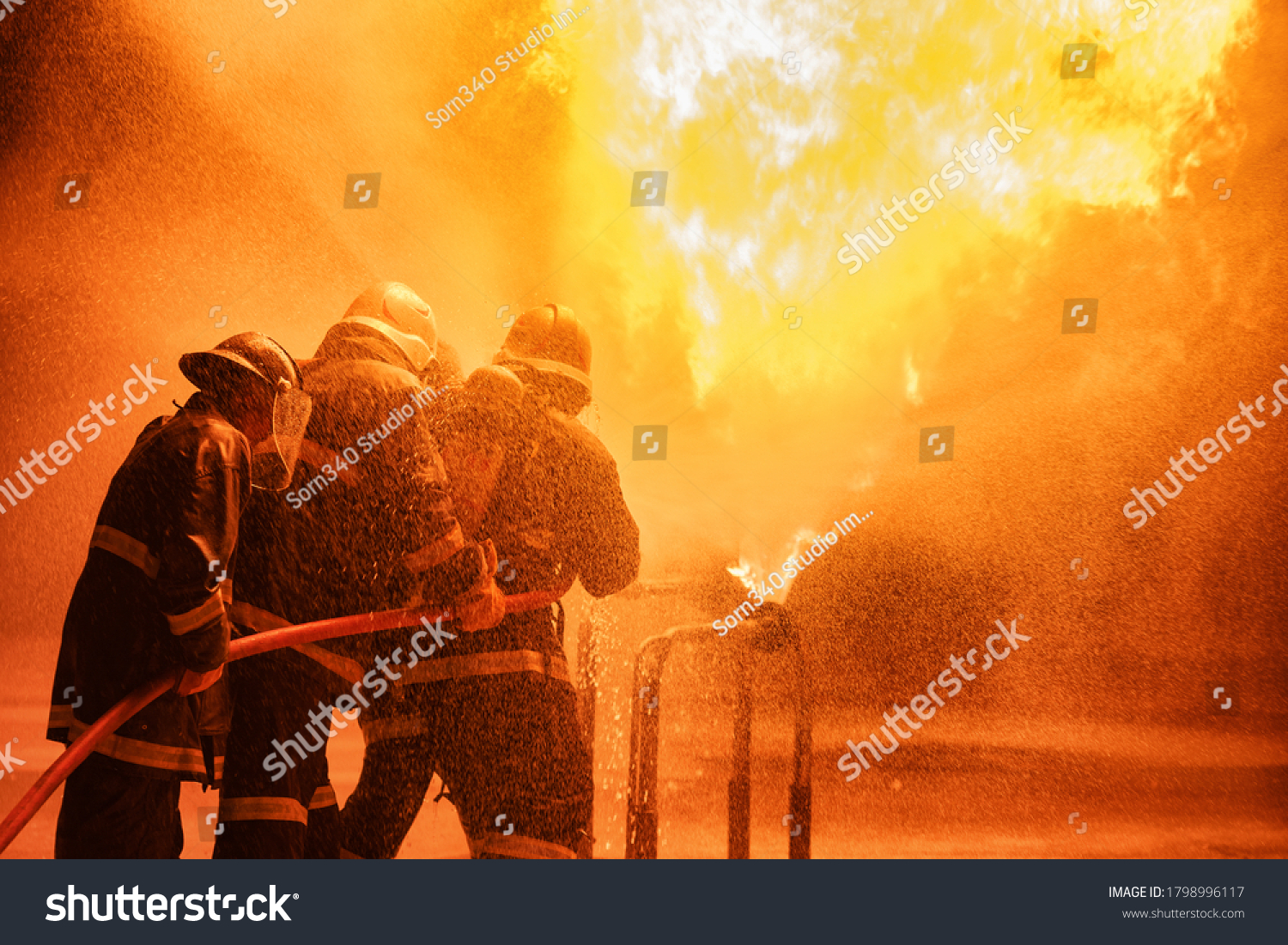 Firefighter using extinguisher or Twirl water fog type fire extinguisher to spray water from hose for fire fighting with fire flame on fuel and control fire for safety in plant of industrial area. #1798996117