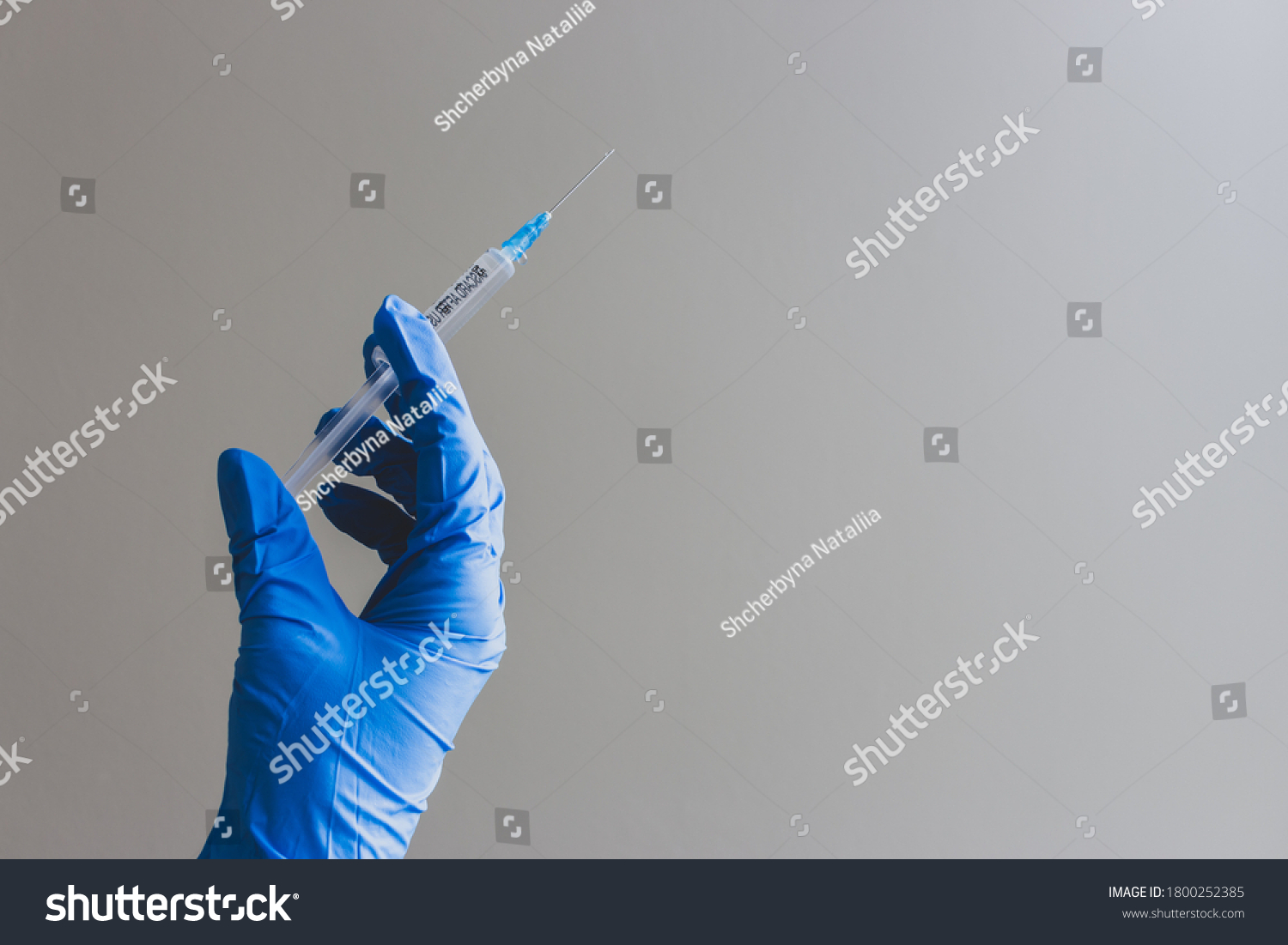Hand in blue glove holding syringe with copy space. Syringe with sharp needle in hand. Medical treatment concept. Laboratory backgrouund. Medicare concept. Vaccination concept.  #1800252385