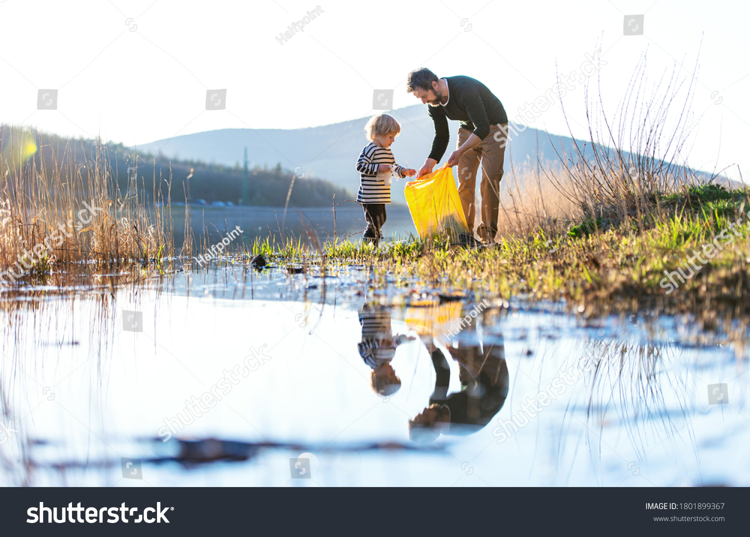 Father with small son collecting rubbish outdoors in nature, plogging concept. #1801899367