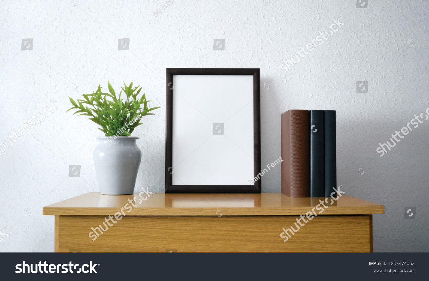 Black frame with plant and books over wooden furniture #1803474052