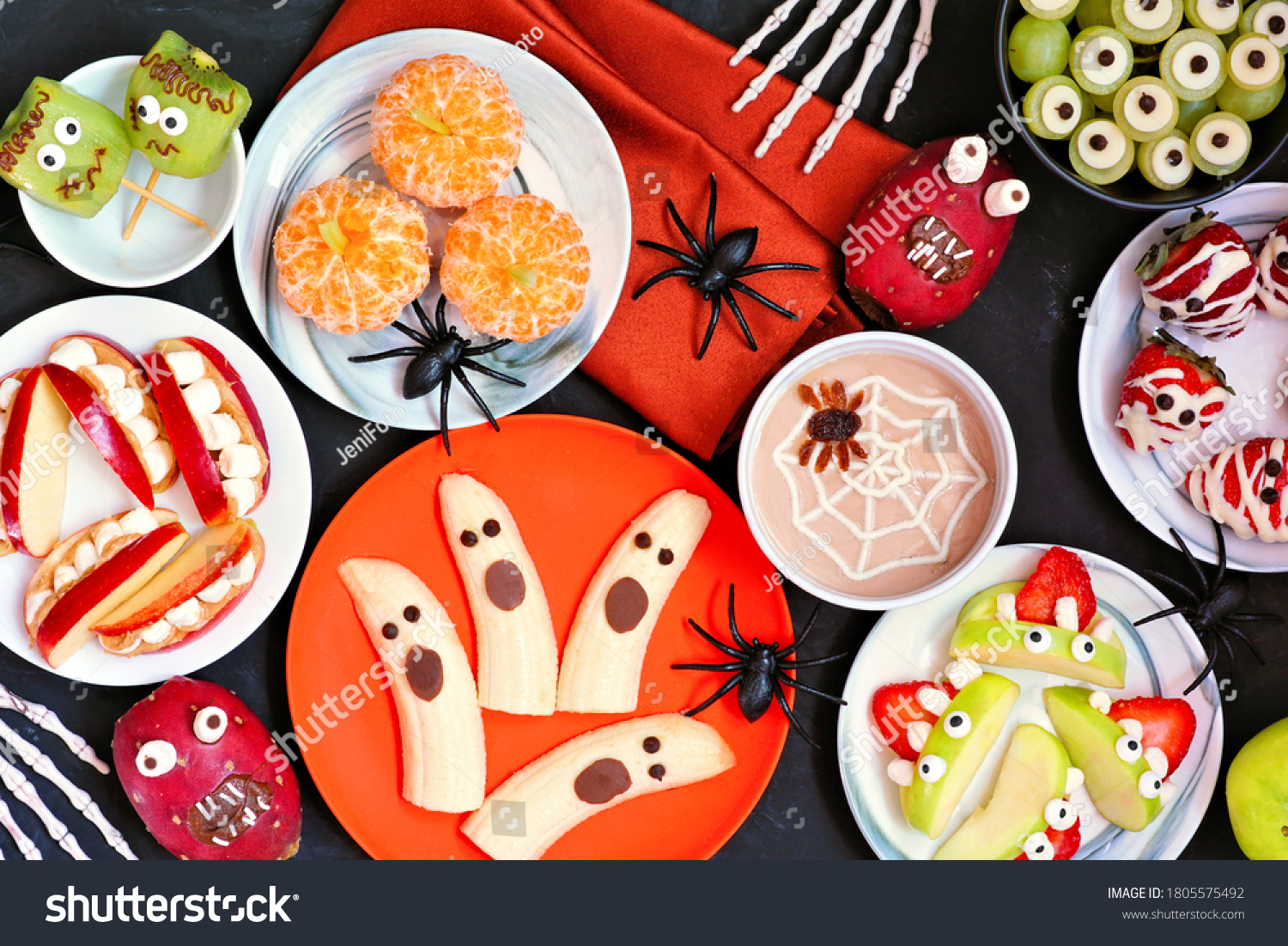 Healthy Halloween fruit snacks. Assorted fun, spooky treats. Top view table scene over a black stone background. #1805575492