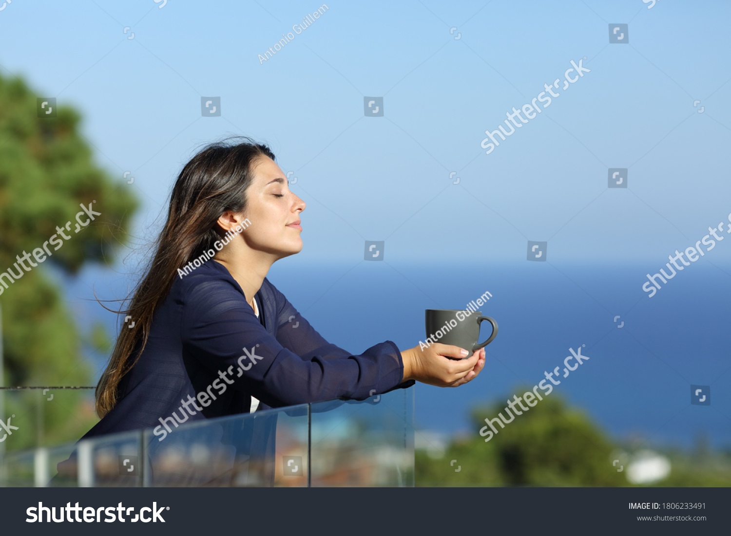 Profile of a relaxed woman in a hotel balcony with a cofee cup on the beach on summer vacation #1806233491