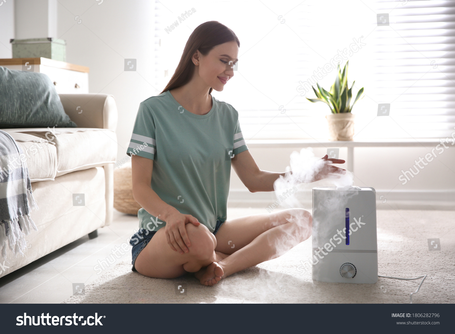 Woman near modern air humidifier at home #1806282796