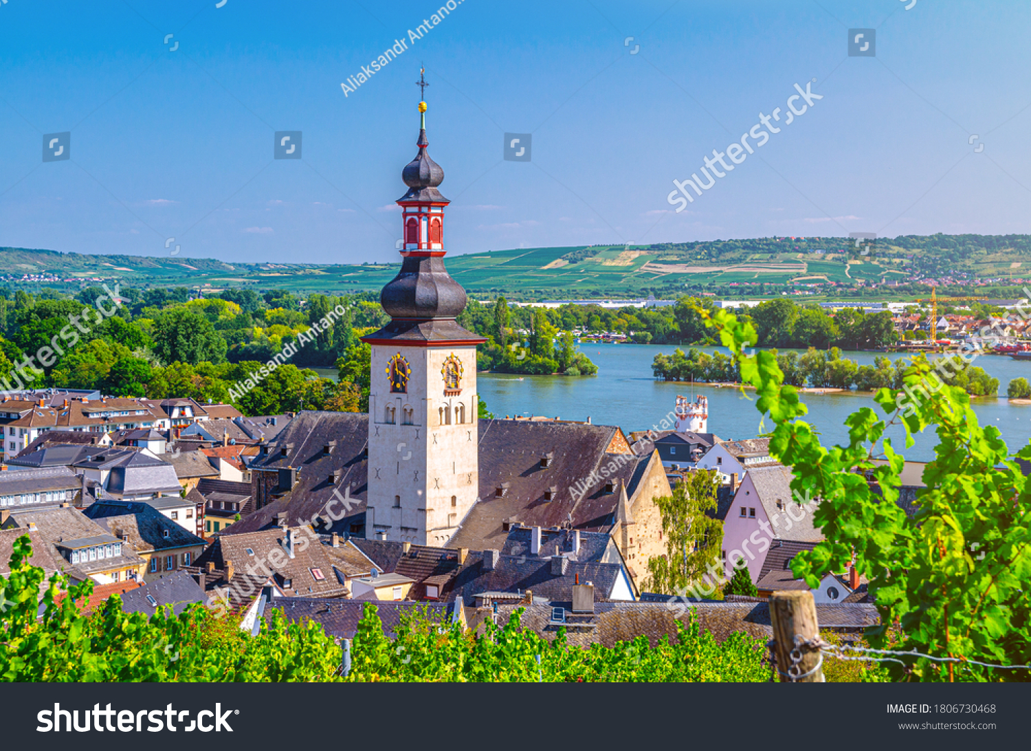 Aerial view of Rudesheim am Rhein historical town centre with clock tower spire of St. Jakobus catholic church and Rhine river, blue sky background, Rhineland-Palatinate and Hesse states, Germany #1806730468