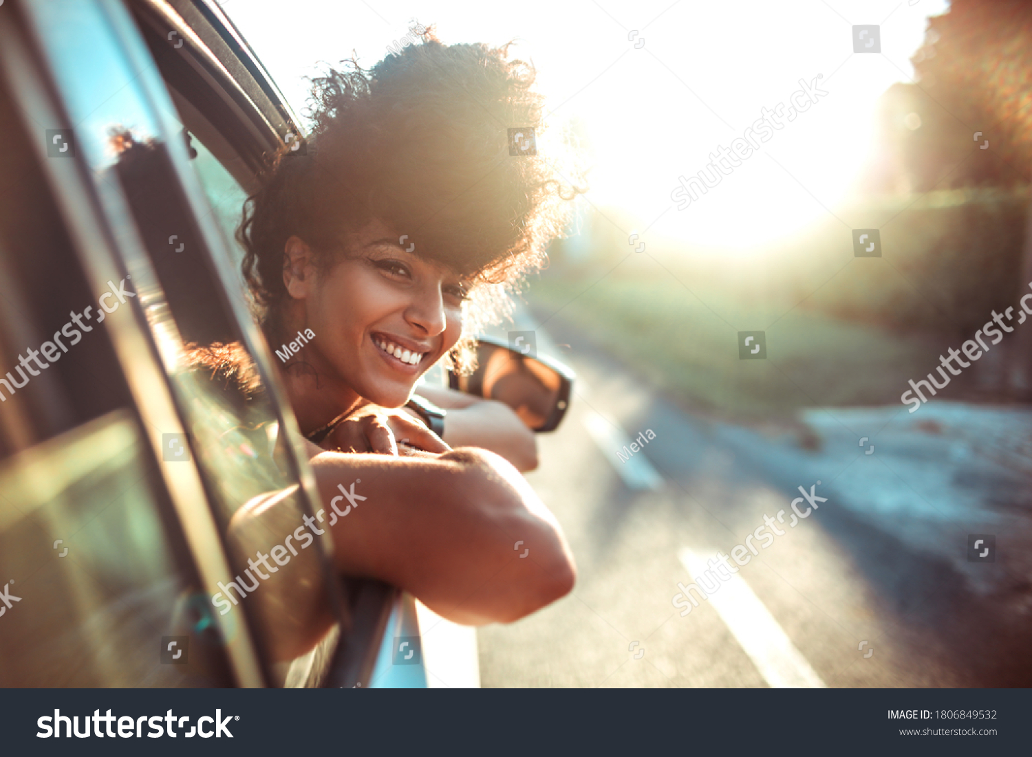 Beautiful curly hair woman enjoying the breeze, looking out of the window's car while having a road trip #1806849532