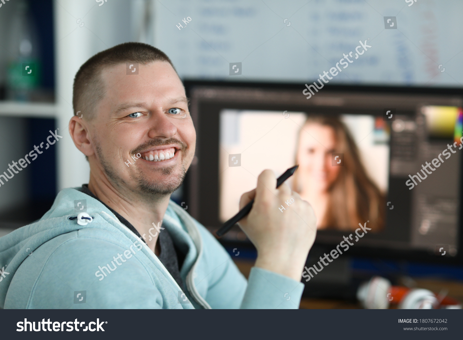 Smiling man holding an electronic pen in his hand from behind on computer background. Learning professions for remote work concept #1807672042