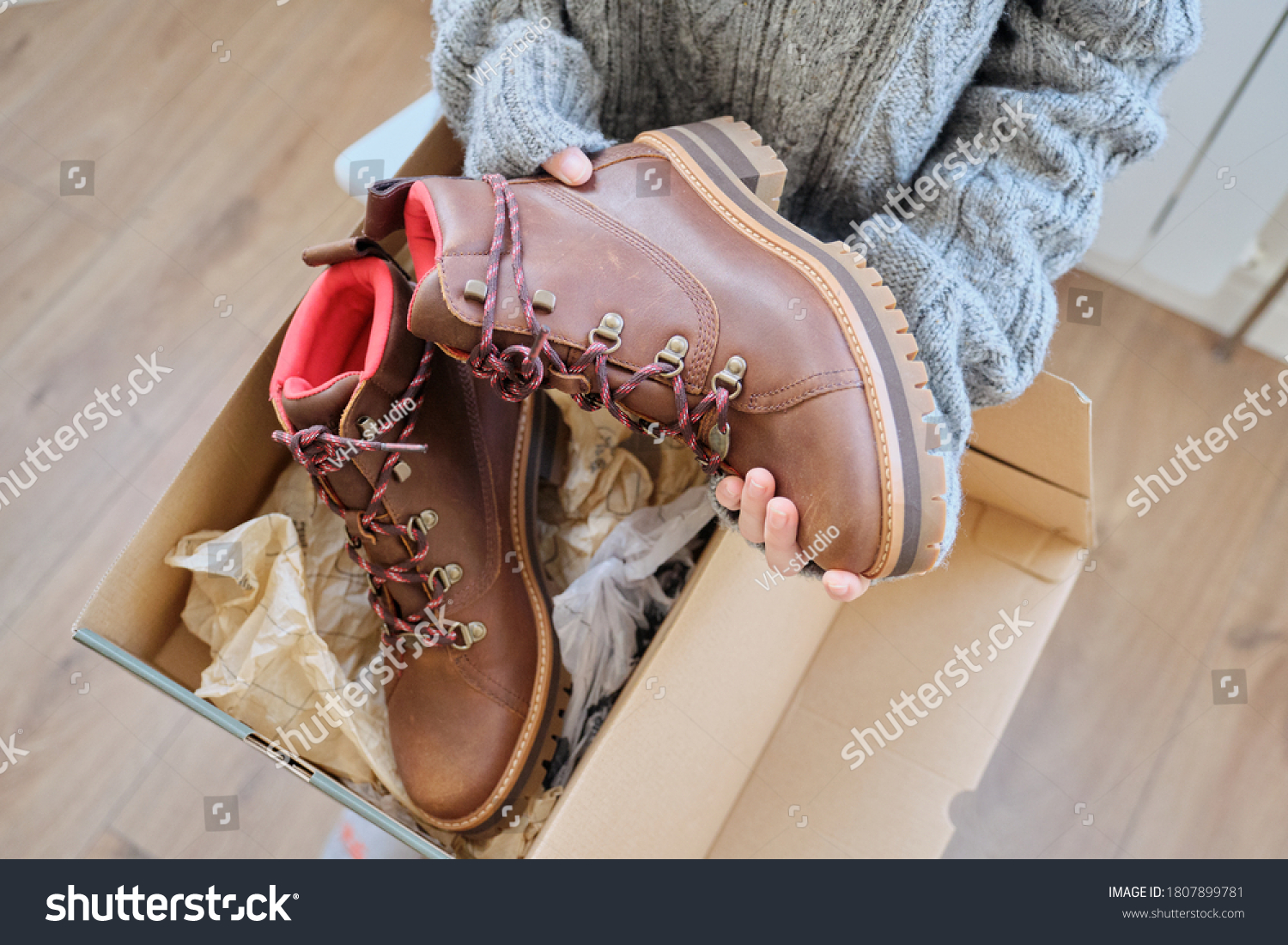 New womens leather brown waterproof hiking winter autumn boots in hands of female, trendy footwear for winter. Unpacking shoes, shopping online from home, shoe fashion store #1807899781
