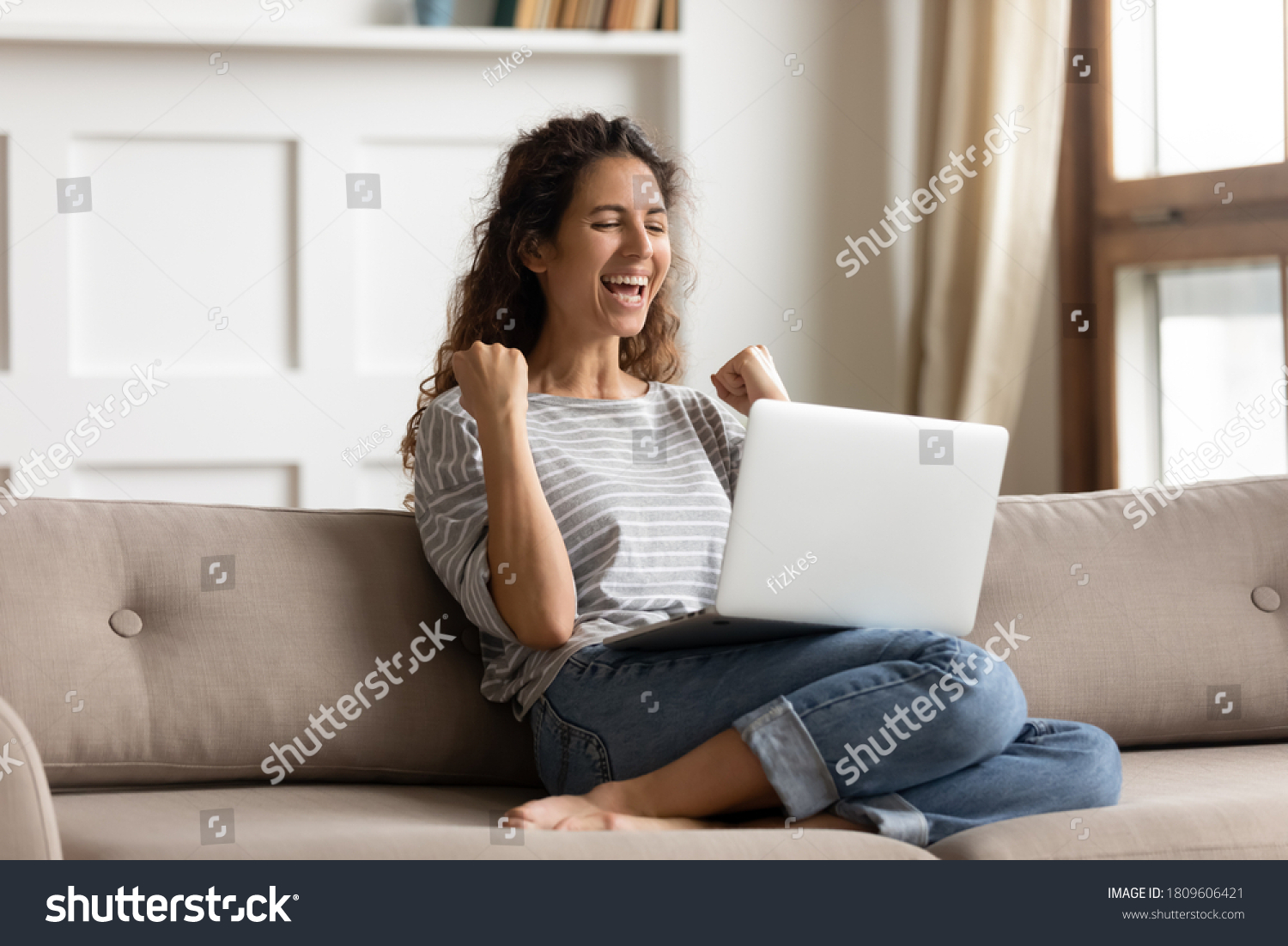 Woman sit on sofa put pc on lap clenched fists scream with joy while read great news on laptop. Gambler celebrate online auction bet victory. Got incredible offer sincere emotions of happiness concept #1809606421