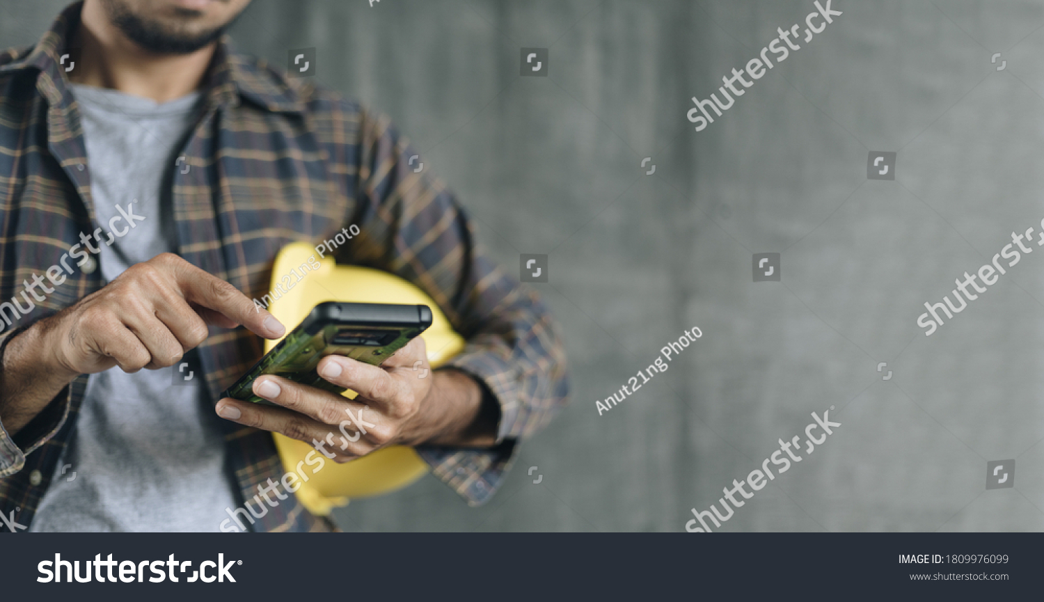 construction worker hands using smartphone on cement wall background with copy space #1809976099