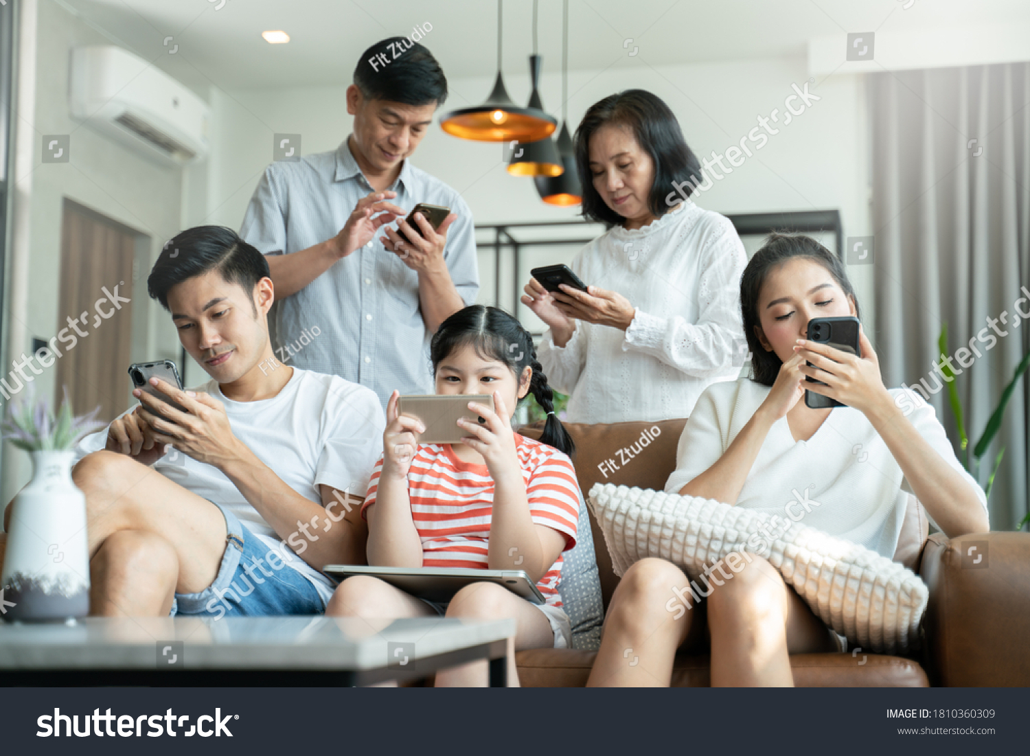 5G Technology for Families concept.Everyone sitting in sofa and using digital devices in living room.Big family grandmother grandfather and kids spending time together at home. #1810360309