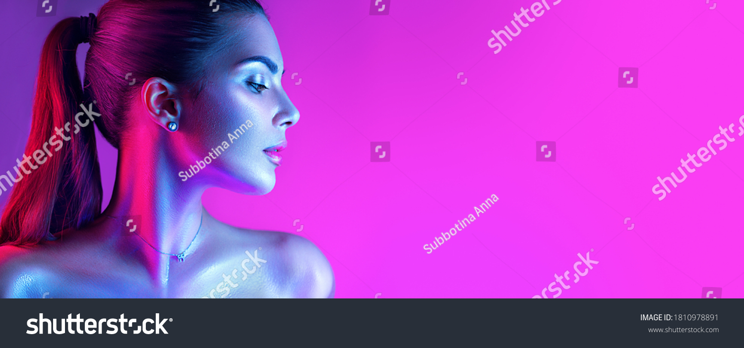 Colorful portrait of a beautiful young woman over purple background. High Fashion model woman in colorful bright neon lights posing in studio, night club. Portrait of beautiful girl in UV. Art design  #1810978891