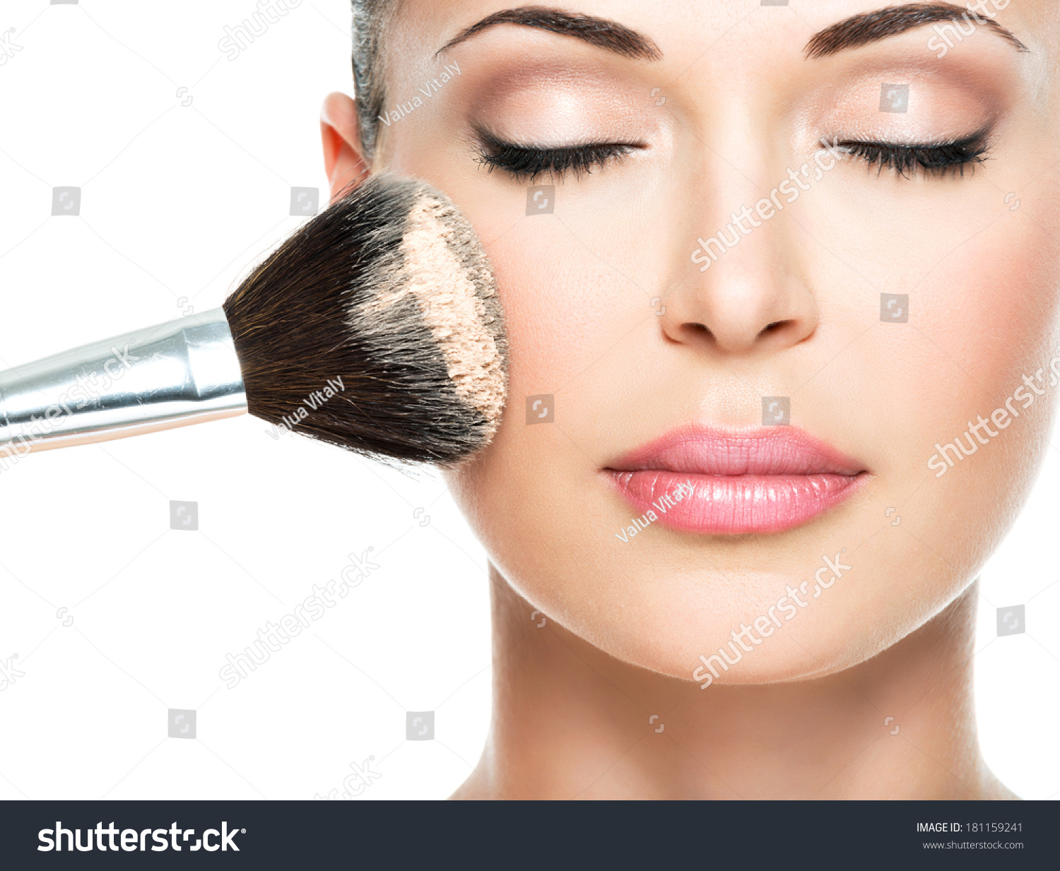 Closeup portrait of a woman  applying dry cosmetic tonal foundation  on the face using makeup brush.  #181159241