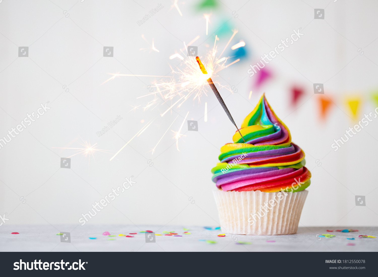 Colorful rainbow cupcake with celebration sparkler #1812550078