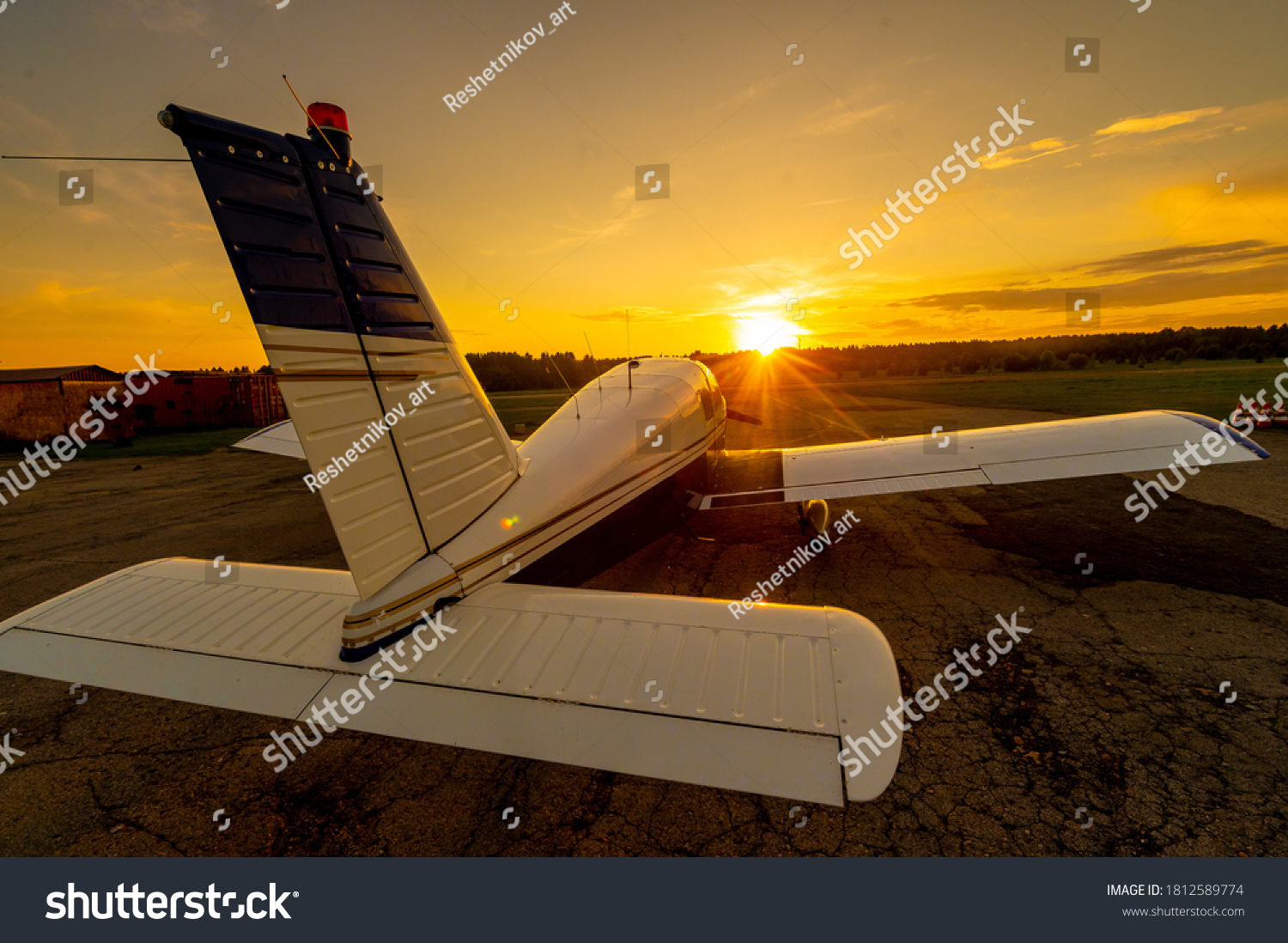 Quadruple aircraft parked at a private airfield. Rear view of a plane with a propeller on a sunset background. #1812589774