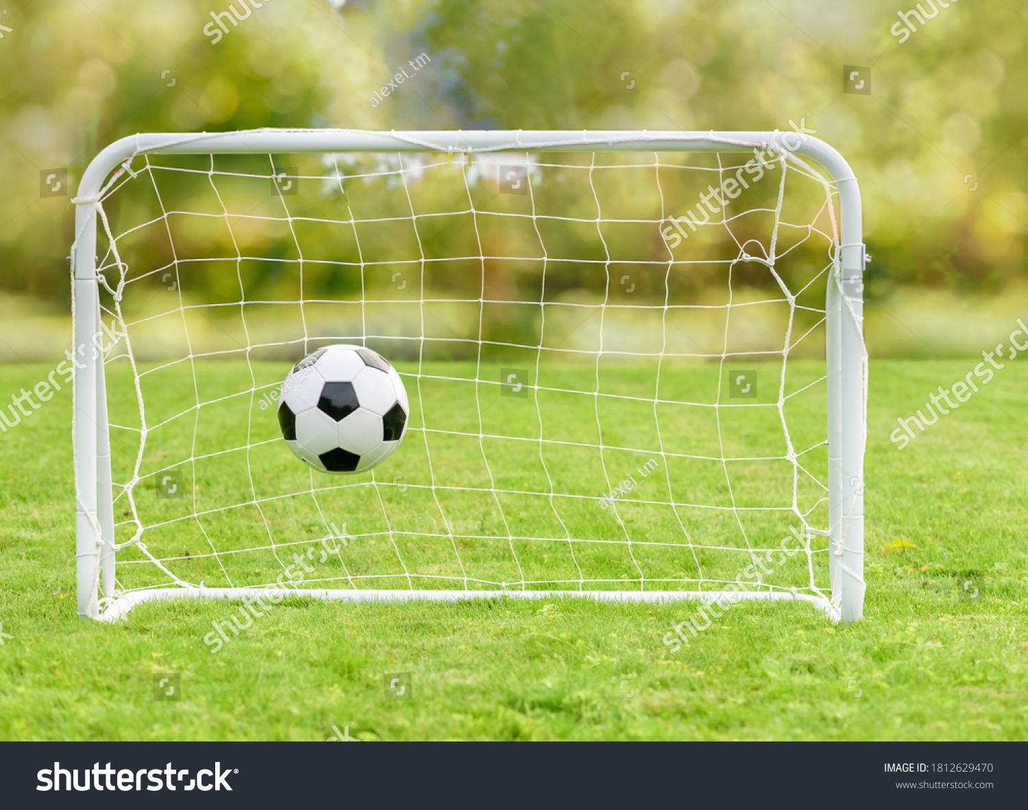Generic football (soccer) ball hits net of mini goal as concept of recreational sport and family fun #1812629470