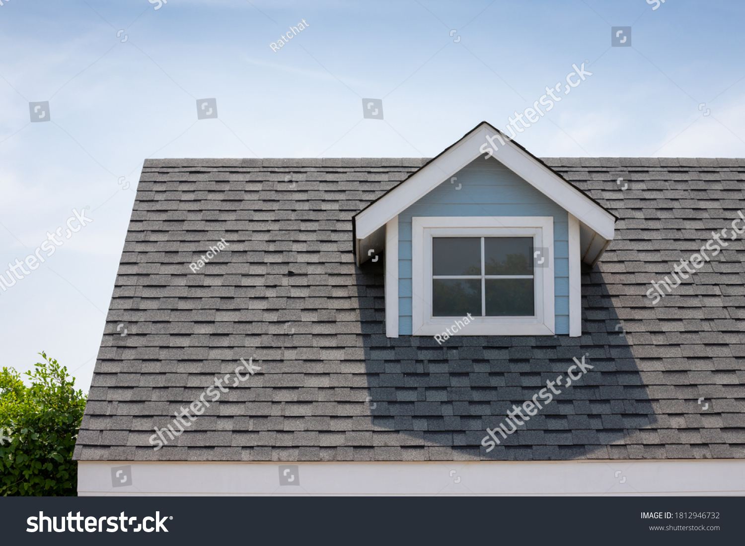 Roof shingles with garret house on top of the house among a lot of trees. dark asphalt tiles on the roof background #1812946732