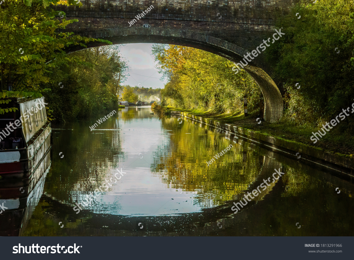 Autumn reflections of Wolfhamcote Bridge No 98, narrowboats, autumn leaves, colors, Oxford Canal near Wolverton, England.  Peaceful autumn light. Picturesque, scenic. Canal life.  Destination holiday. #1813291966