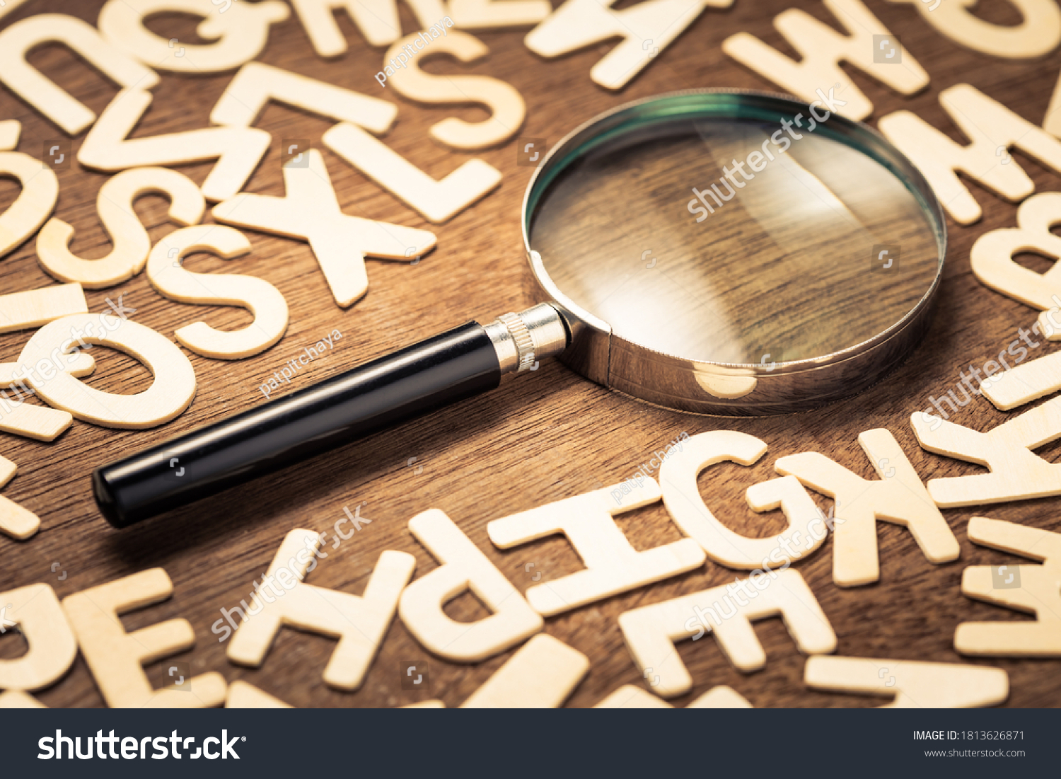 Magnifying glass with many wood letters of English alphabets, searching words to communicate, learning English concept #1813626871