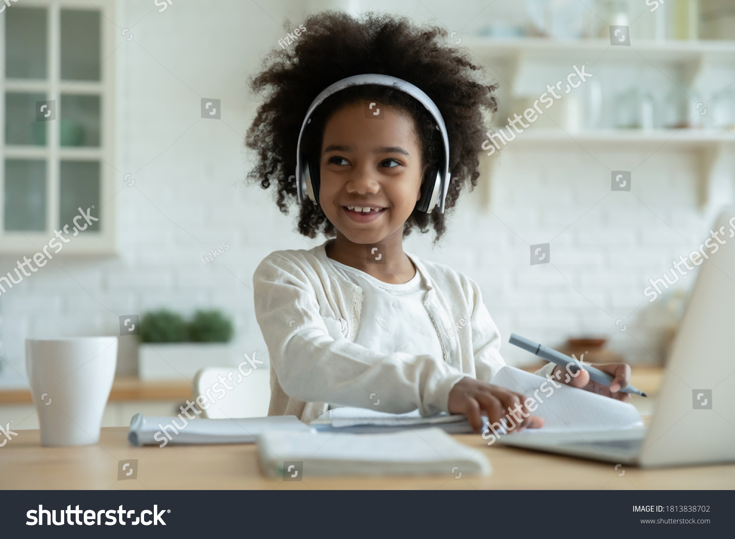 Distracted from e-learning happy playful small mixed race kid girl in headphones looking away. Smiling pretty african american little child enjoying listening lecture, remote education concept. #1813838702