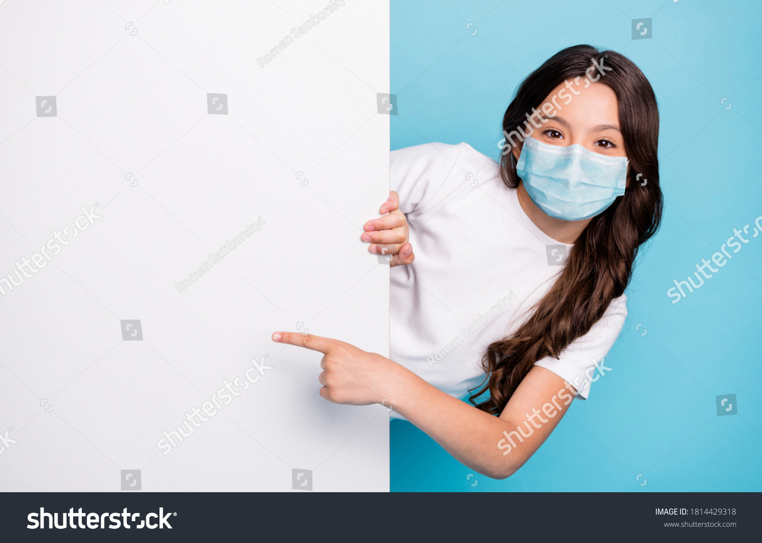 Close-up portrait cheerful cheery wavy-haired girl demonstrating empty space ad advert point finger covid outbreak news wear medical mask isolated bright shine blue color background #1814429318