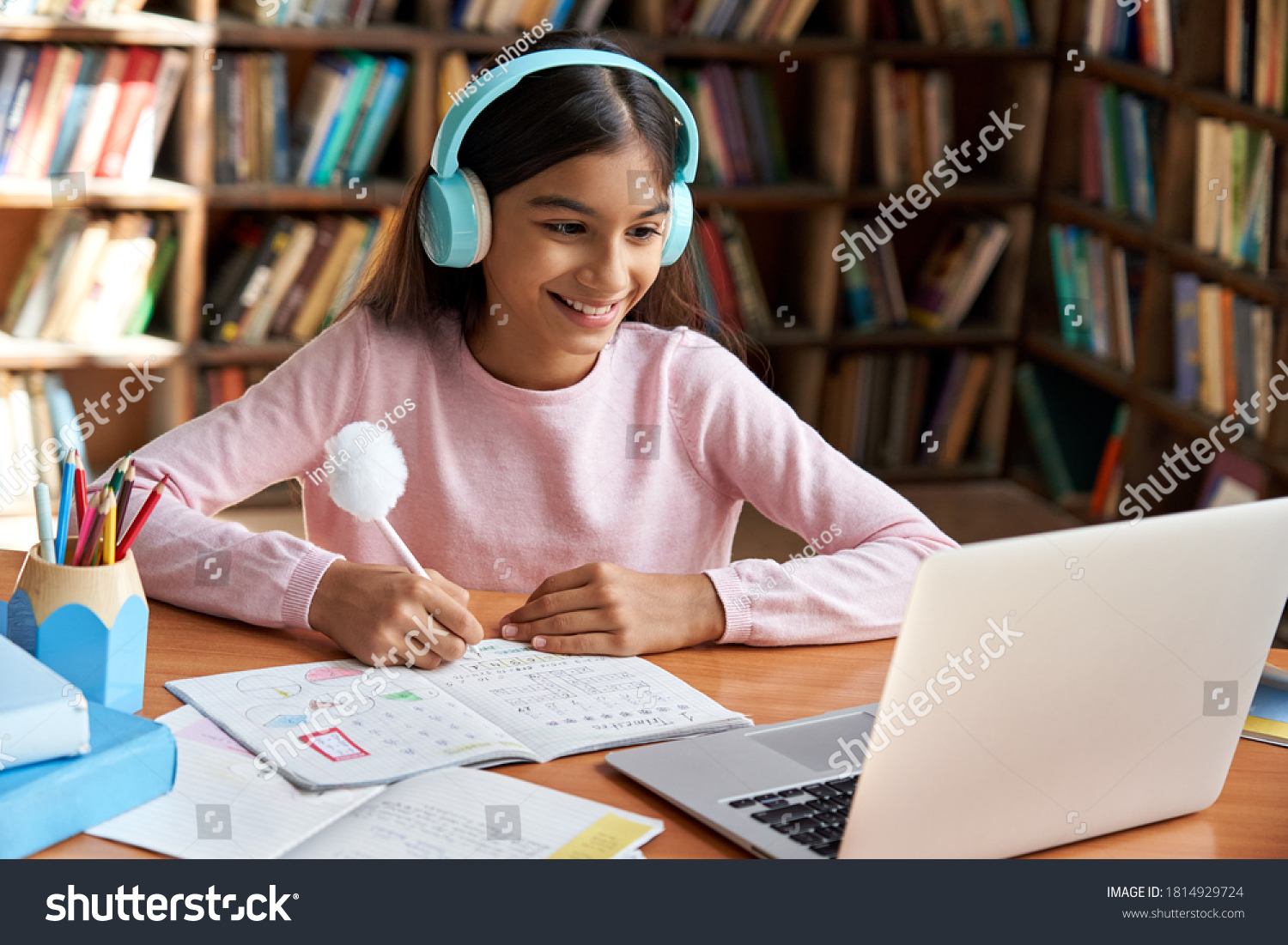 Happy indian latin preteen girl school pupil wearing headphones distance learning online at virtual class with teacher tutor on laptop by video conference call, watching tv lesson at home. #1814929724