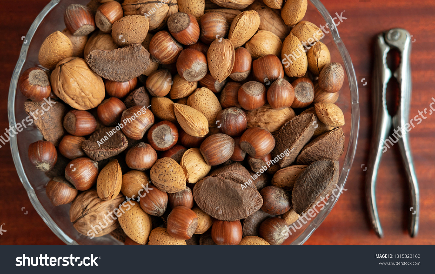 Assortment of whole nuts, walnuts, almonds, hazelnuts and Brazil nuts in a bowl with a nut cracker on a side, nutritious snack cracked and eaten in autumn or winter months as a special holidays treat. #1815323162