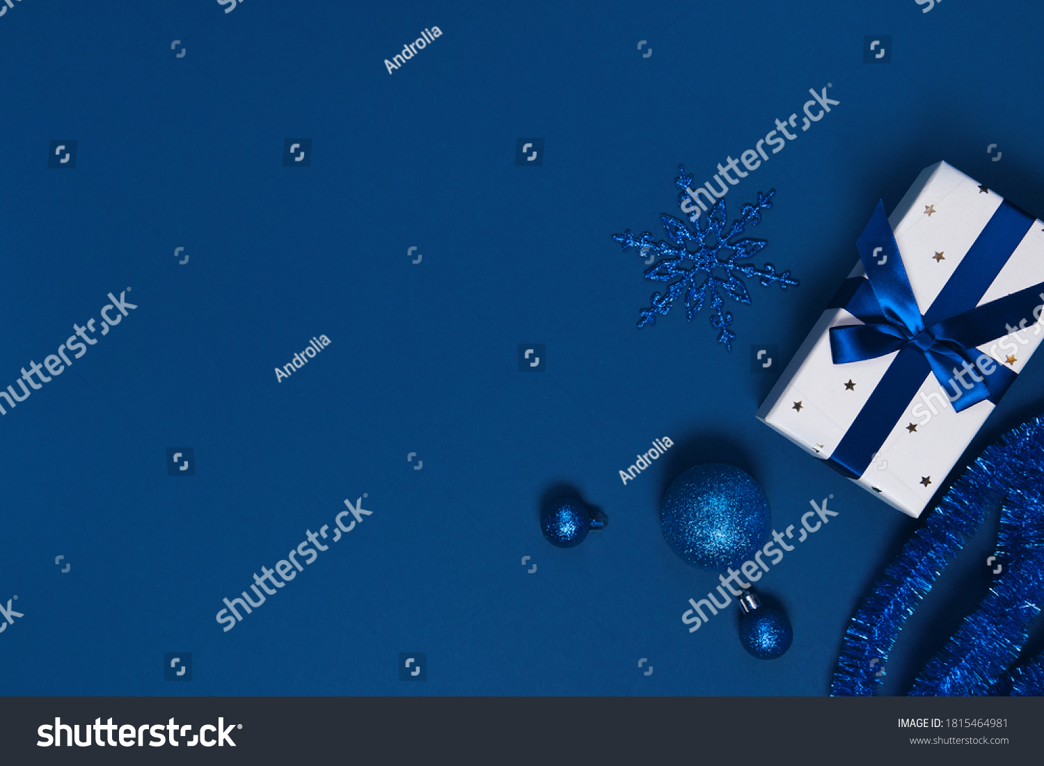 Present box wrapped with a ribbon, decorative balls and snowflake on colorful paper background. Christmas gift. Holiday concept. Image is with copy space. Flat lay. Top view #1815464981