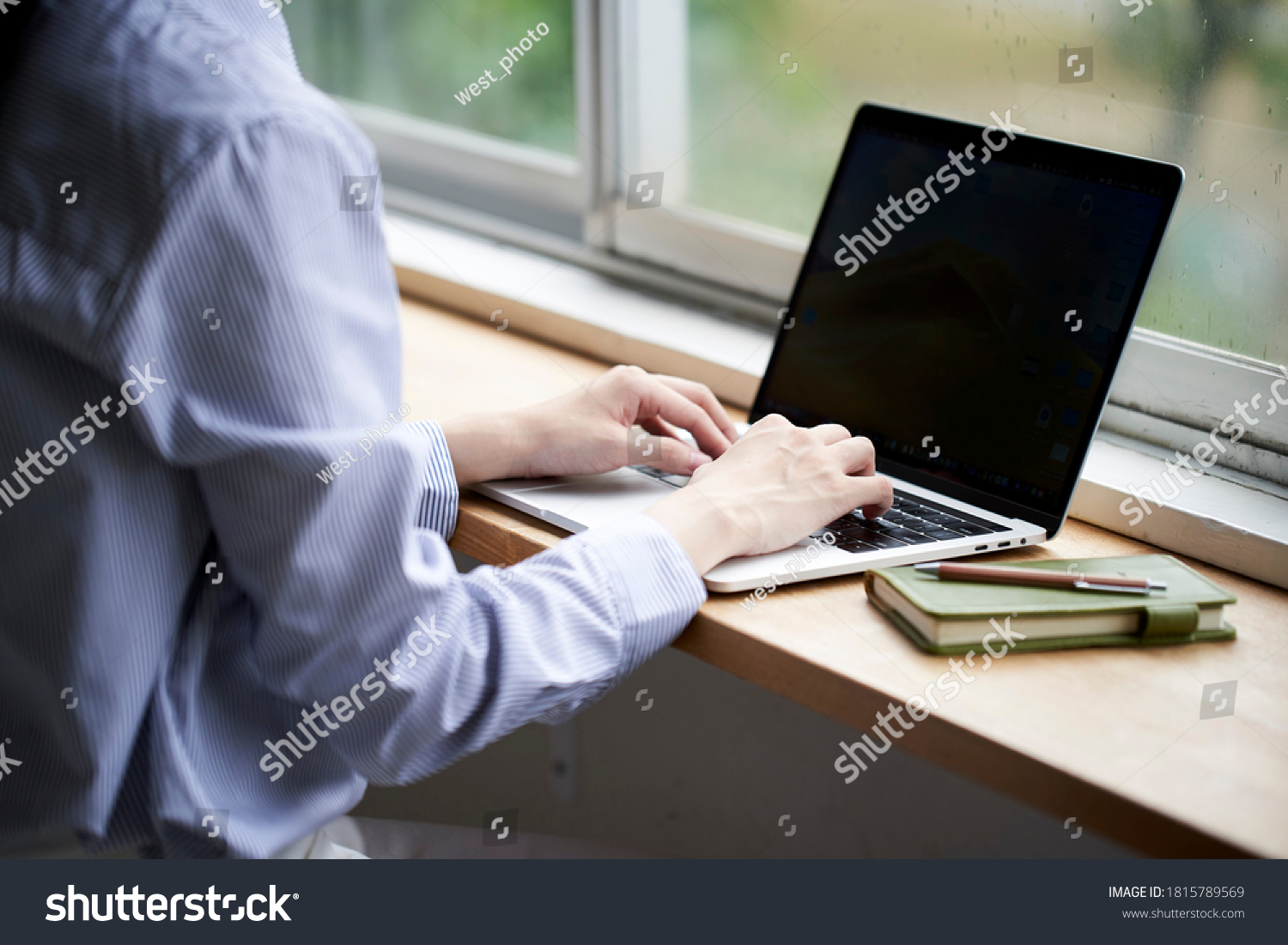 A young woman operating a computer by the window #1815789569