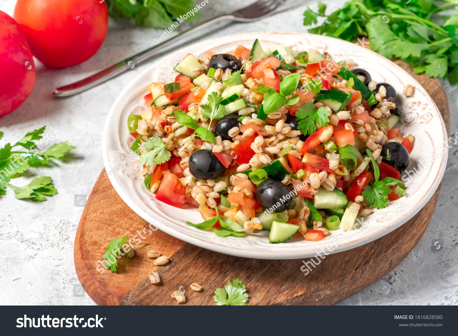 Pearl barley salad with vegetables in a plate close-up. Boiled pearl barley with tomatoes, cucumbers, olives, parsley and basil. Vegan and vegetarian food. #1816828580