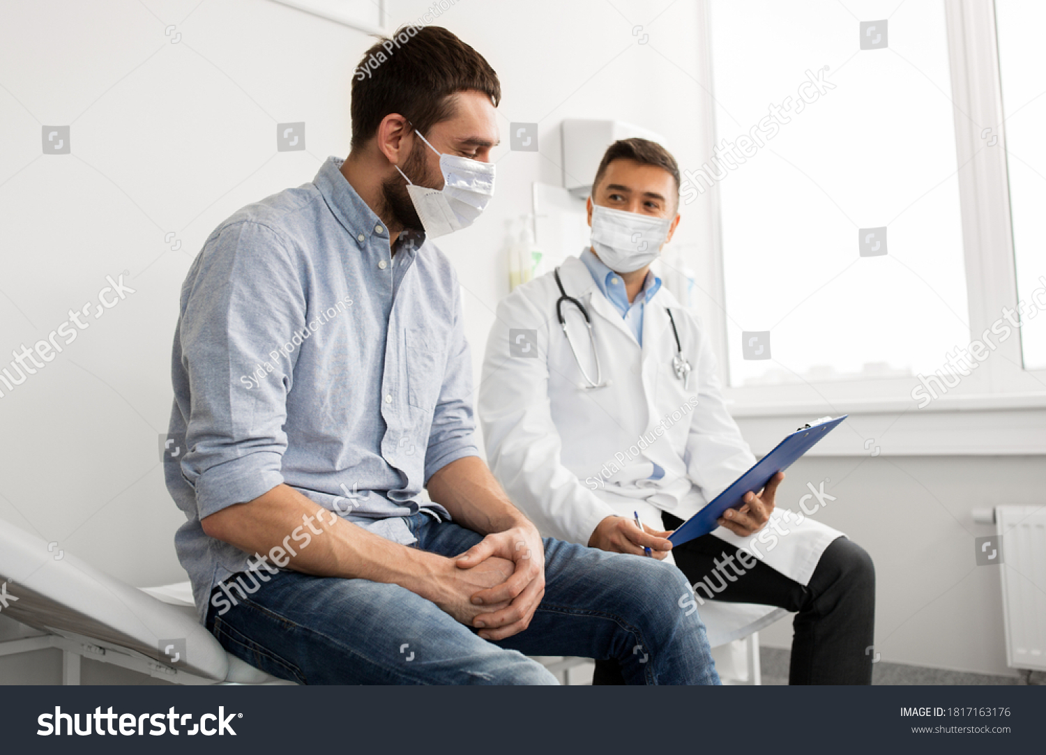 medicine, healthcare and pandemic concept - male doctor wearing face protective medical mask for protection from virus disease with clipboard and young man patient meeting at hospital #1817163176