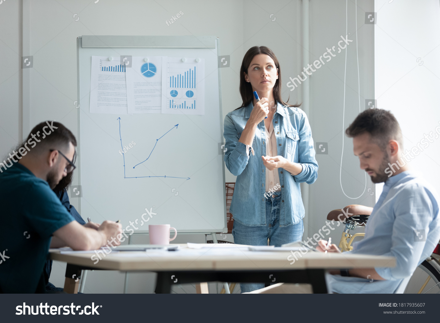 Stressed young businesswoman employee feeling nervous before flip chart presentation, standing near white board in modern boardroom, speaker mentor coach remembering speech, waiting decision #1817935607