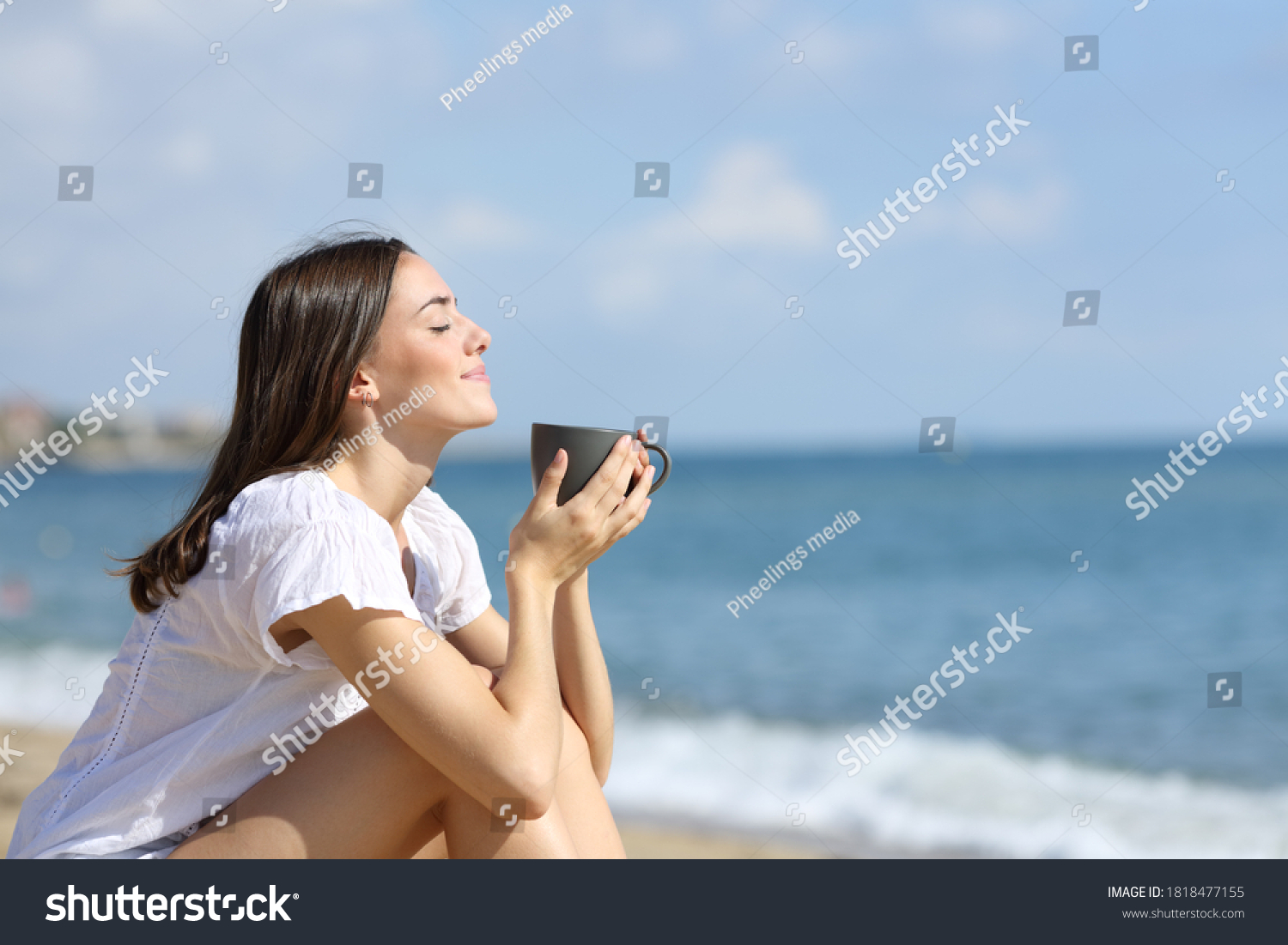 Side view portrait of a relaxed girl smelling coffee on the beach on summer vacation #1818477155