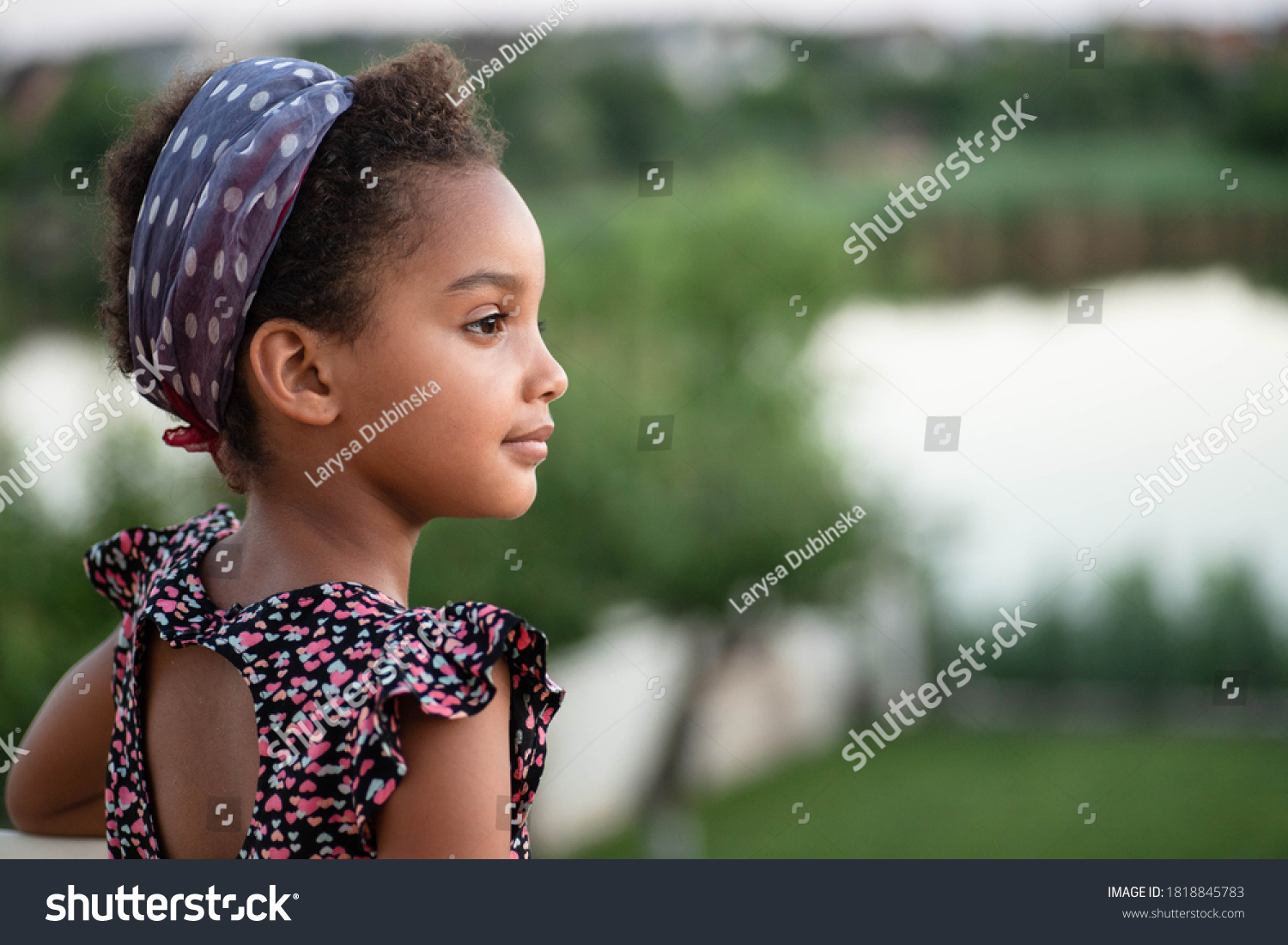 Portrait of beautiful mixed race kid in nature. Beautiful profile. Soft light. Afro hair. Child looks to the side. Concept of childhood, travel, future, dreams, peace. Copy space. Young girl outdoor. #1818845783