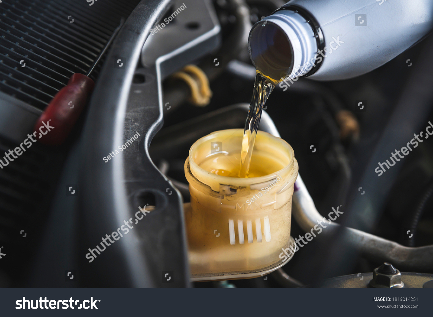 Auto mechanic filling DOT 4 brake fluid in brake fluid reservoir. #1819014251