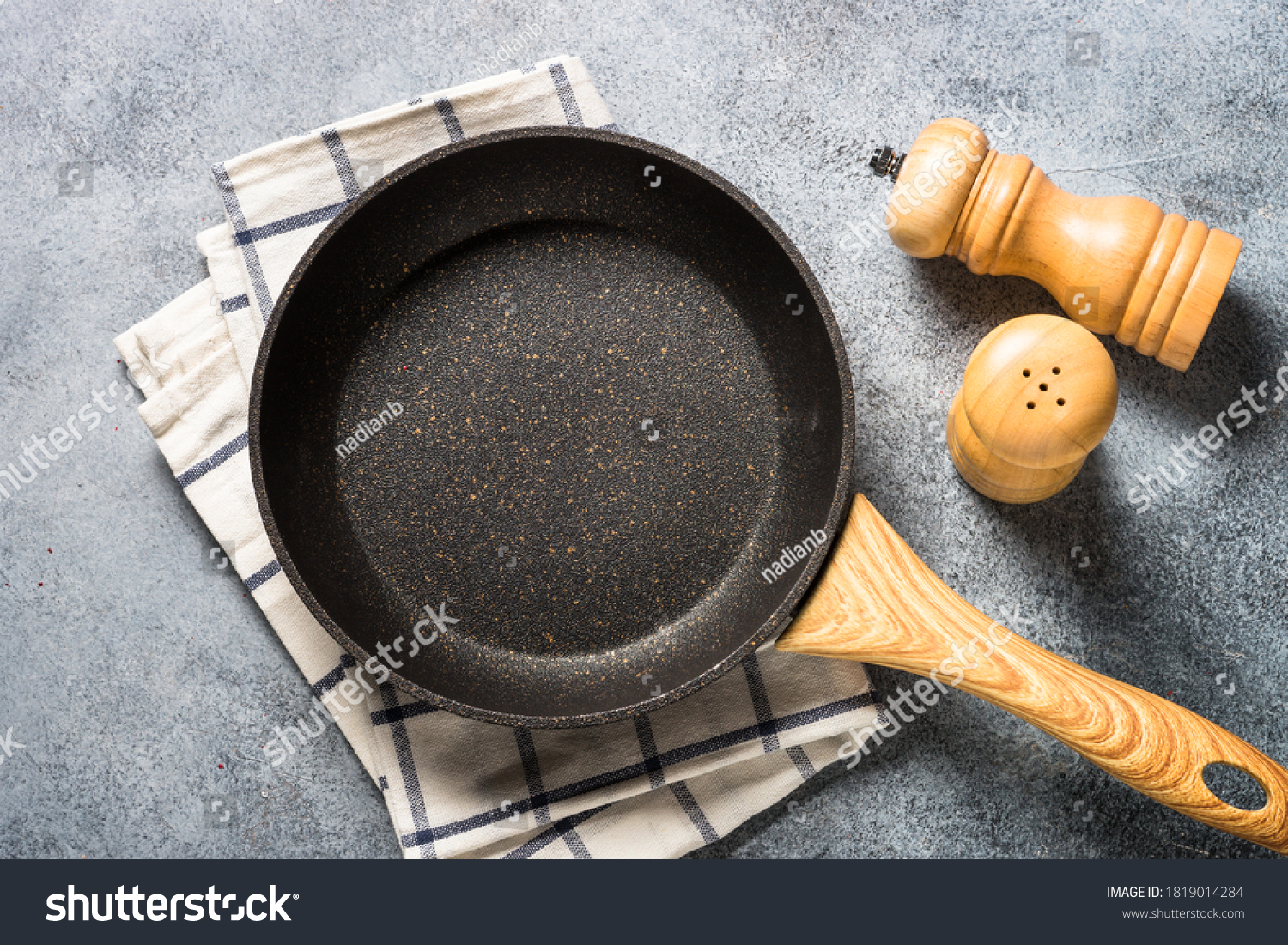Frying pan or skillet with stone nonstick coating on light stone table. Top view with copy space. #1819014284