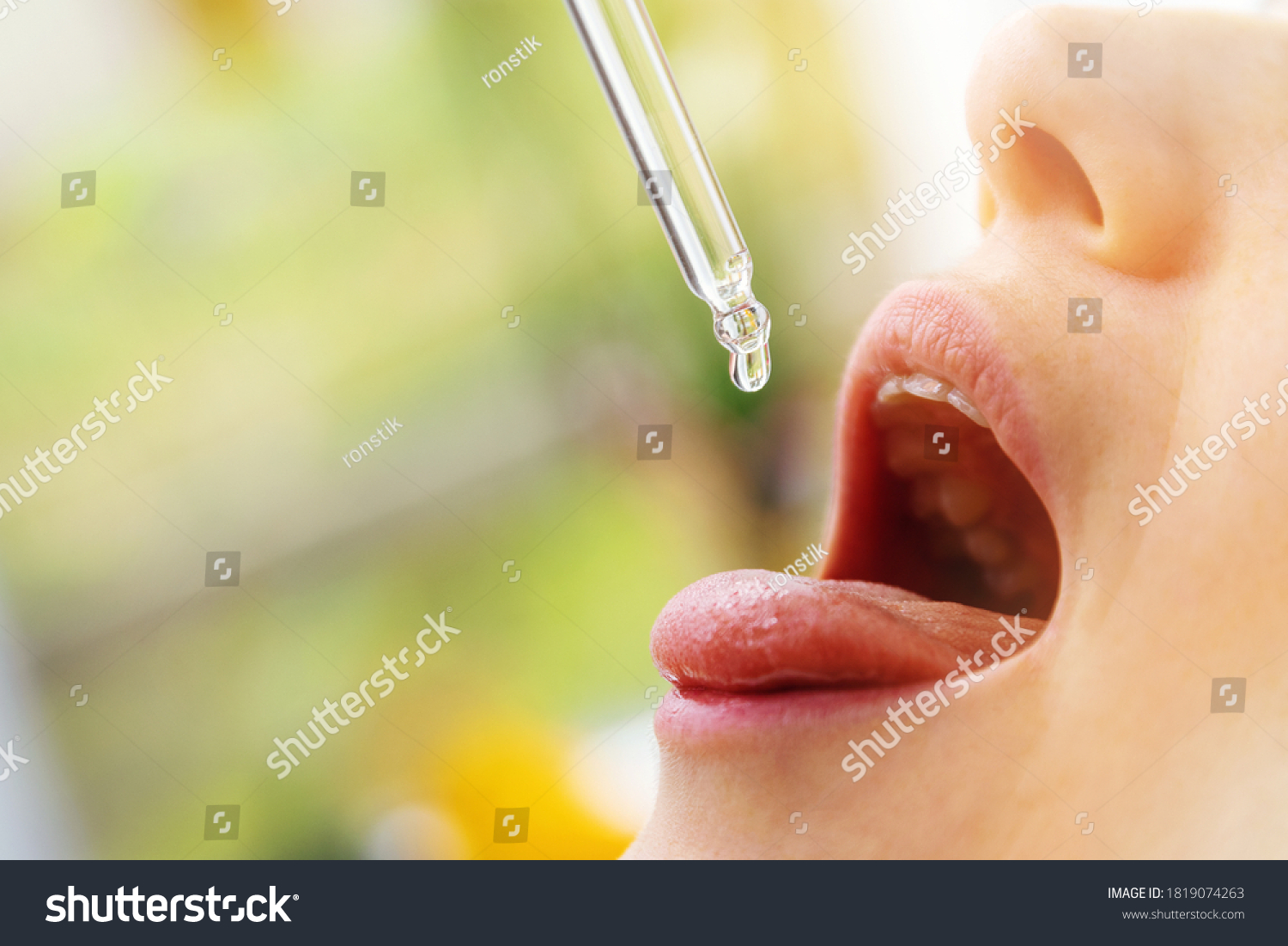 woman taking vitamin d drops in mouth from dropper. copy space #1819074263