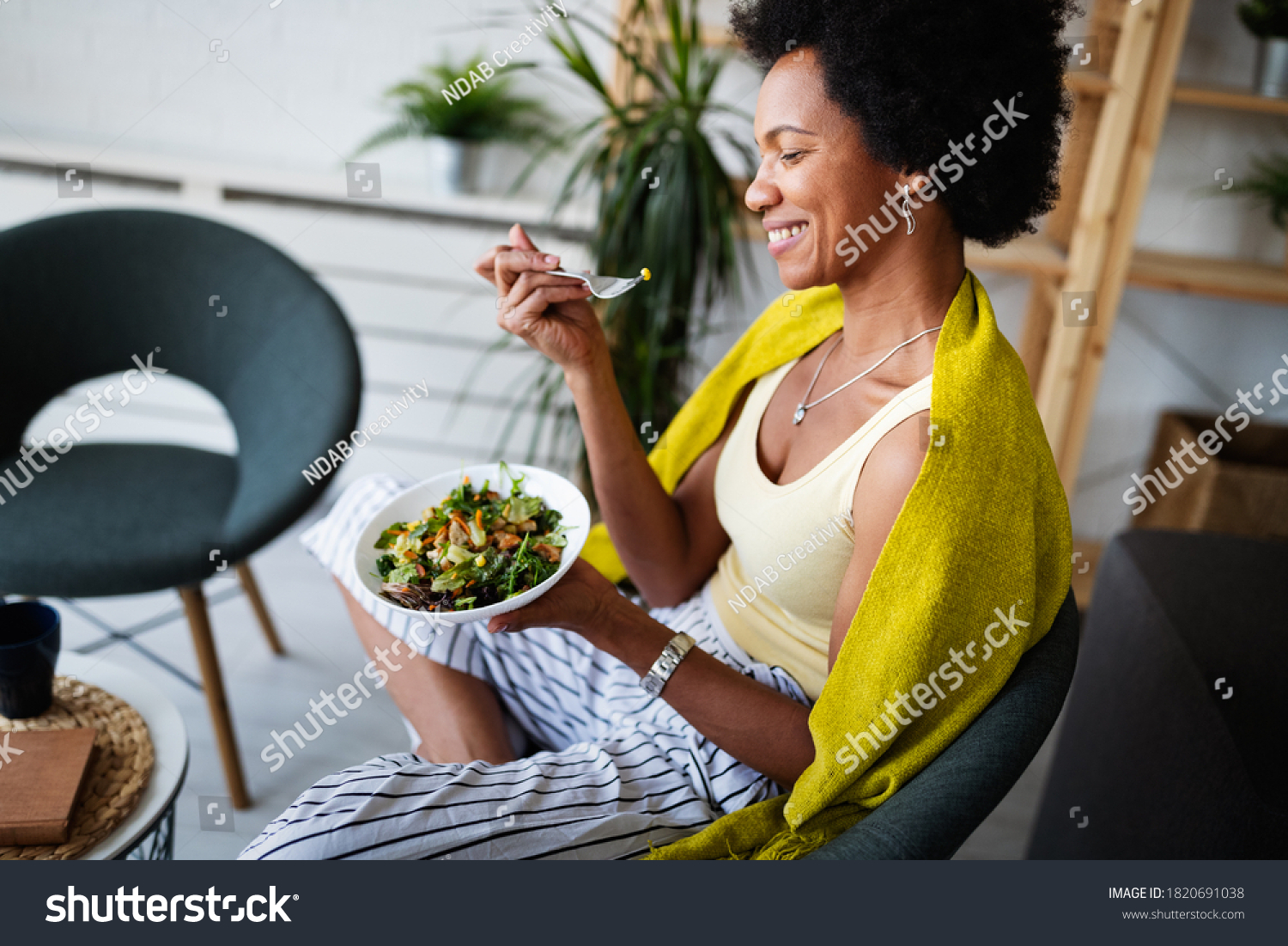 Beautiful afro american woman eating vegetable salad at home. #1820691038