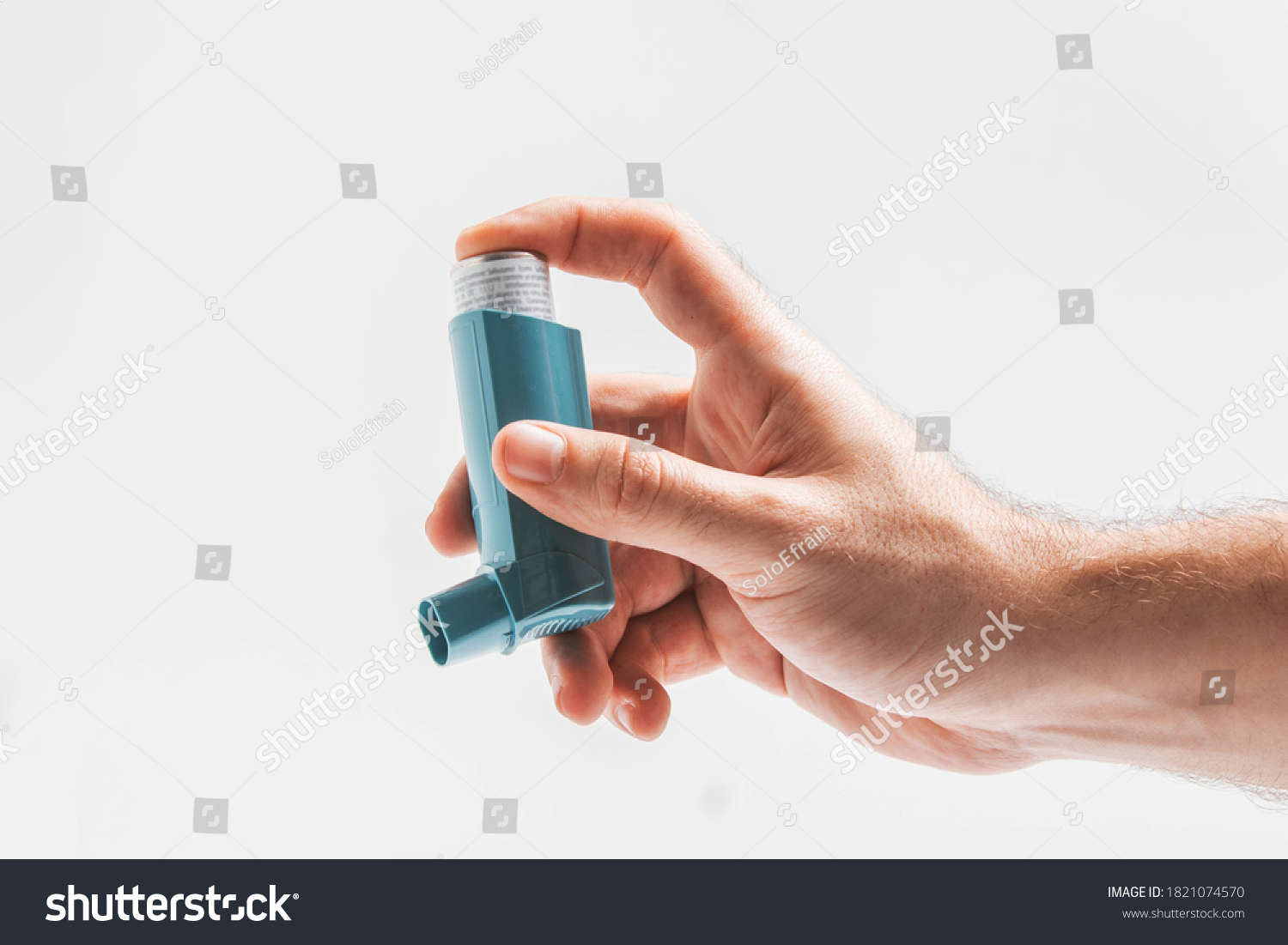 Male hand pressing his bronchodilator medicine with salbutamol for patients with asthma, allergy and Chronic Obstructive Pulmonary Disease isolated on white background.