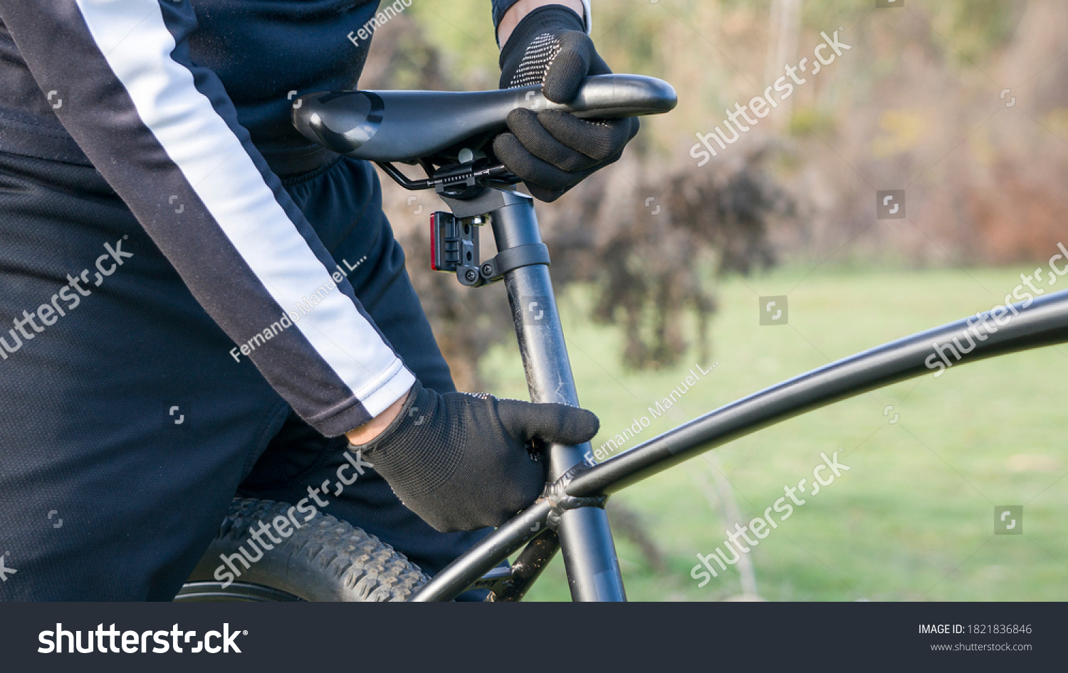 cyclist with black gloves adjusting black seat #1821836846