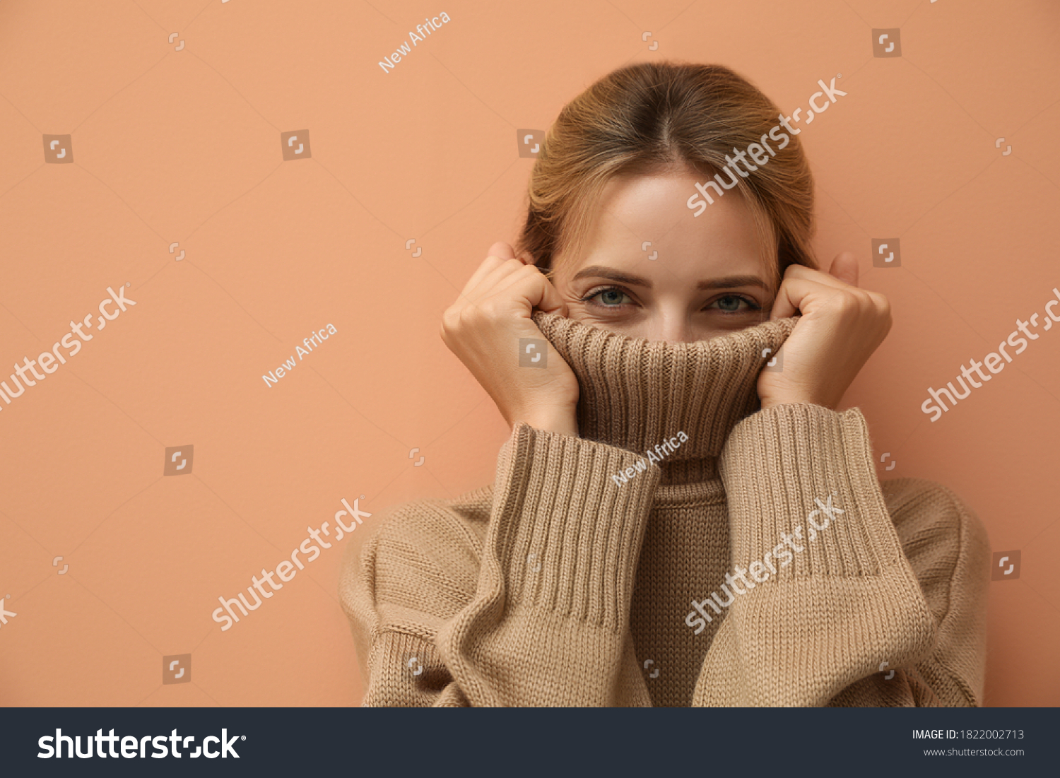 Beautiful young woman wearing knitted sweater on light brown background. Space for text #1822002713