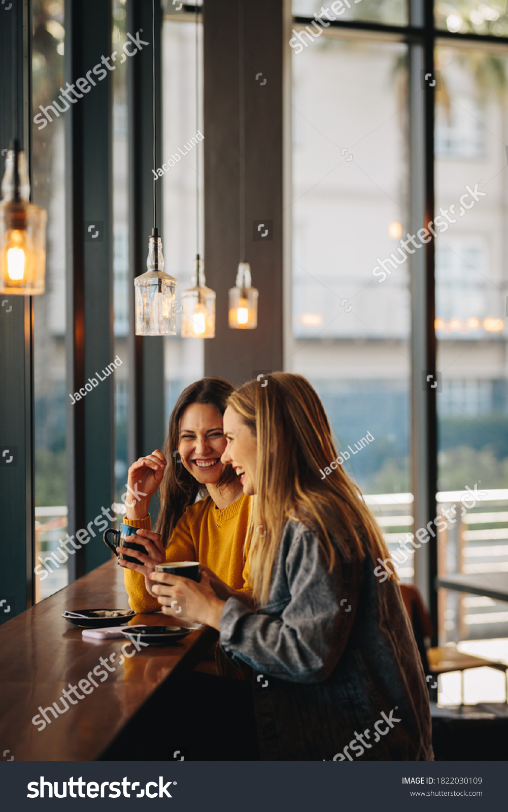 Cheerful female friends sitting together at cafe table. Smiling women meeting in a coffee shop and chatting. #1822030109