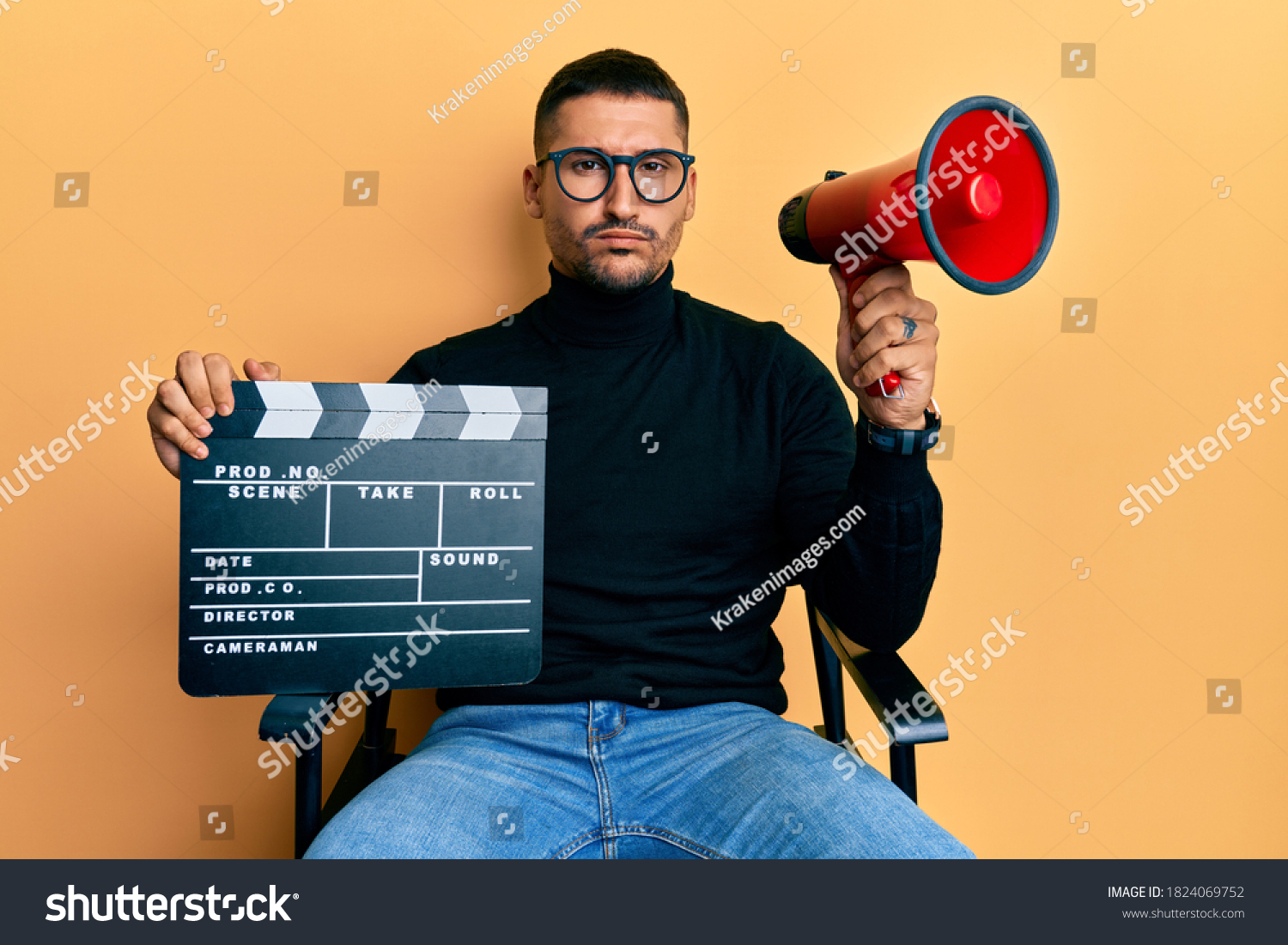 Handsome man with tattoos holding video film clapboard and megaphone skeptic and nervous, frowning upset because of problem. negative person.  #1824069752