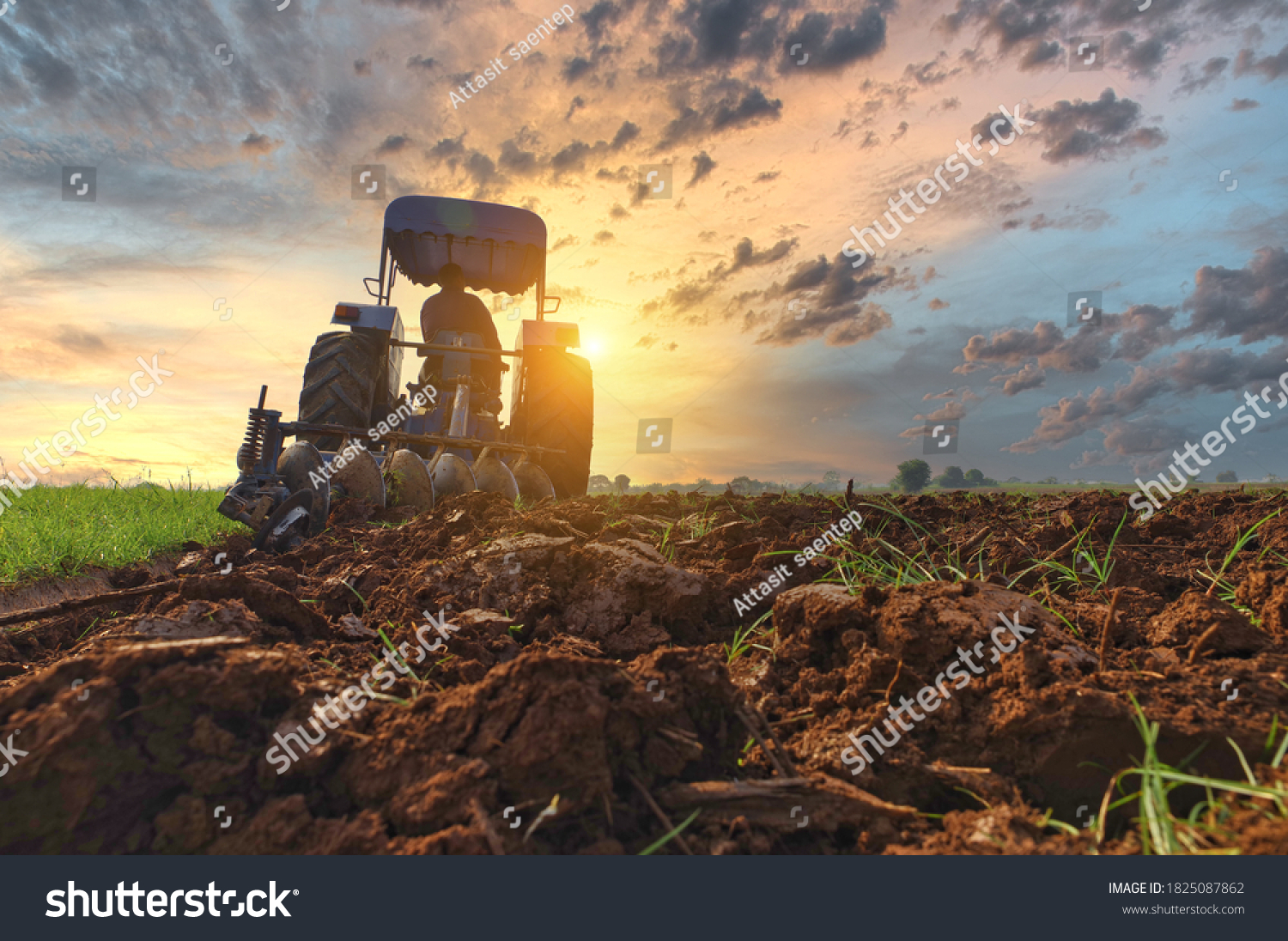 Farmer in tractor preparing land with seedbed cultivator as part of pre seeding activities in early spring season of agricultural works at farmlands Cultivated field Agronomy farming husbandry concept #1825087862